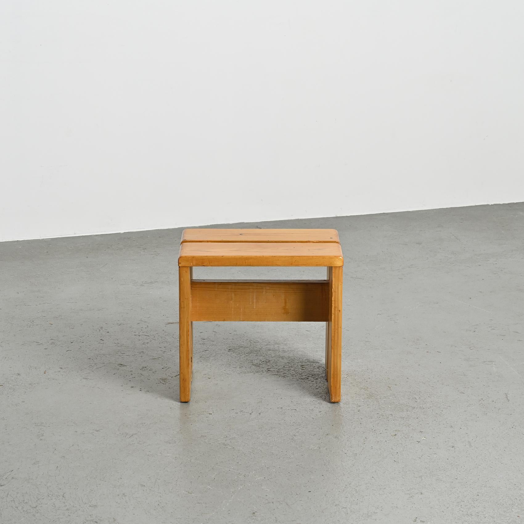 Diese mit Präzision aus massivem Kiefernholz gefertigten Hocker haben eine elegante umgekehrte U-Form und eine charmante Patina. Diese Hocker wurden speziell als Modell für das Skigebiet Les Arcs 1800 ausgewählt, wo Charlotte Perriand 20 Jahre lang