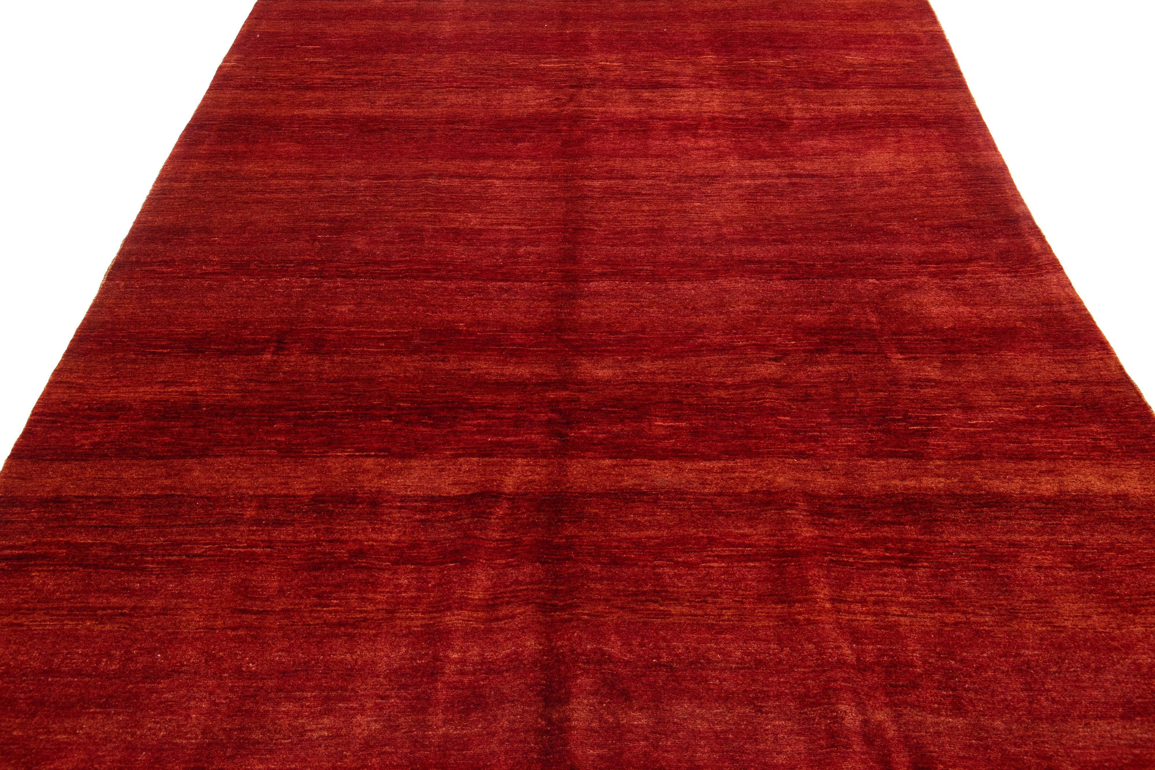 Beautiful modern Gabbeh-style hand-knotted wool rug with a red-rust color field. This piece has a gorgeous all-over solid design.

This rug measures: 6'9