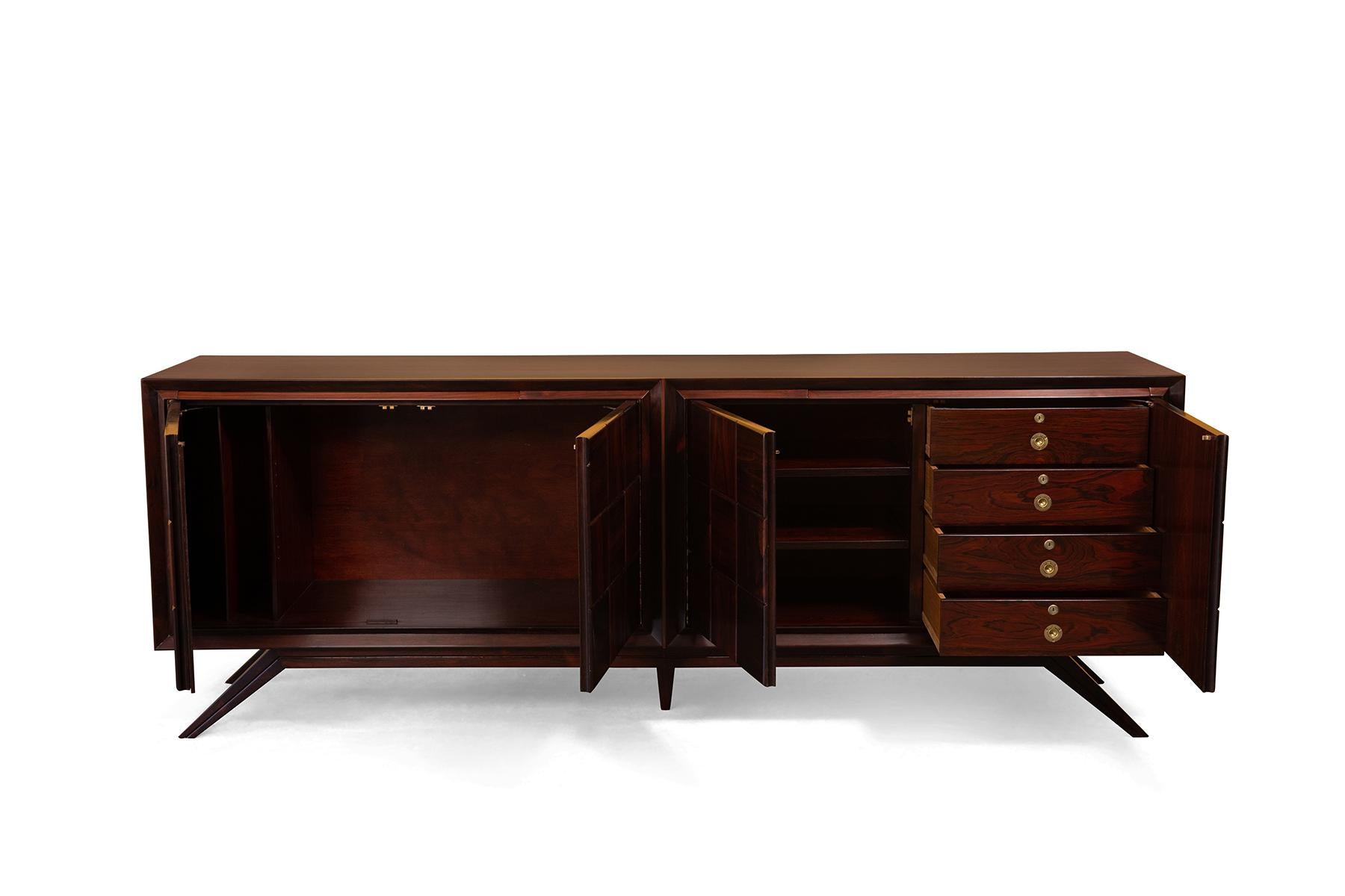 Solid rosewood credenza, circa early 1960s. This monumental example has solid patchwork rosewood on the doors and incredibly sculptural splayed legs. Interior has a combination of drawers and shelves. Because of the materials it is quite heavy so