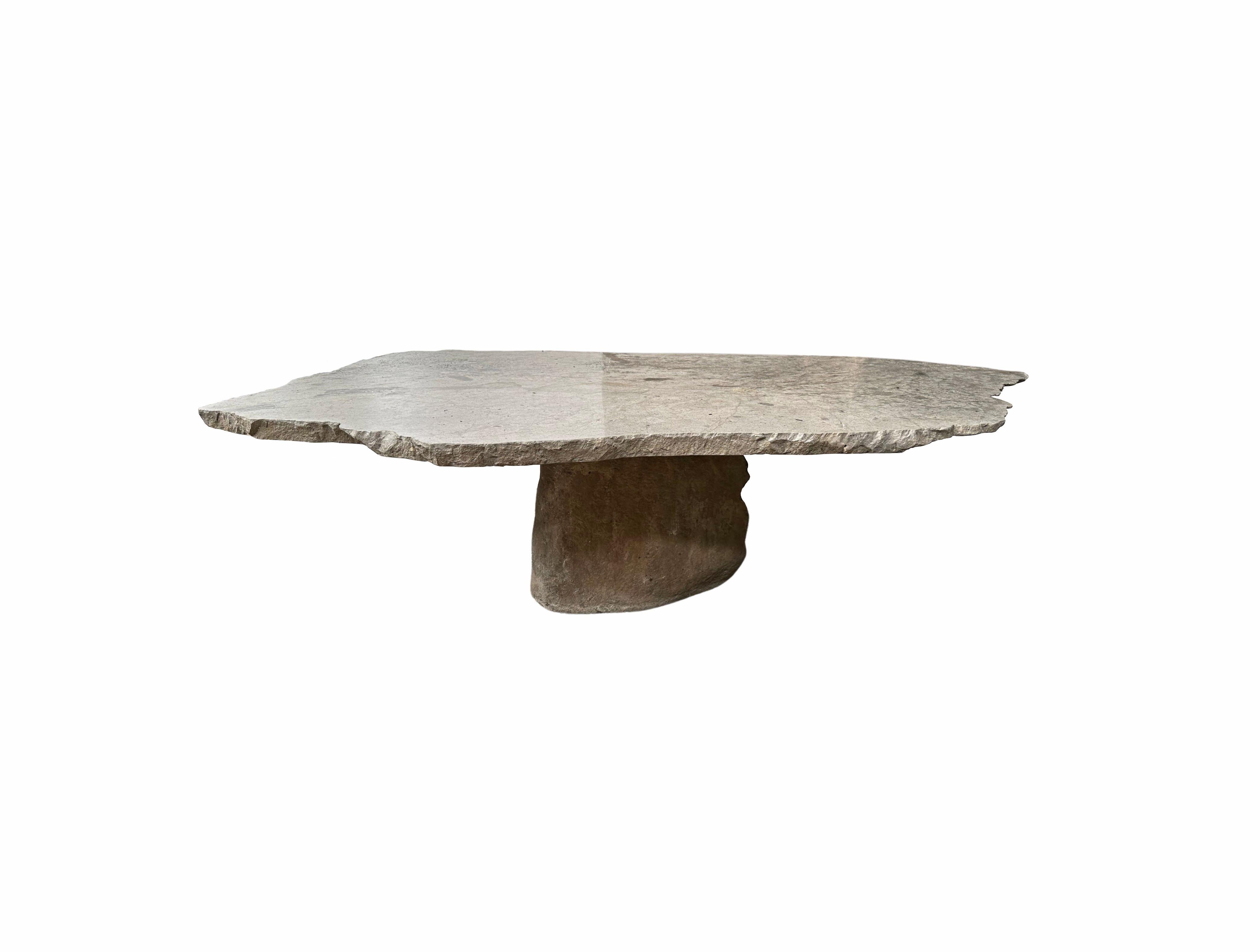A incredibly heavy and solid stone table with a wonderful organic form. This sculptural object was crafted from solid stone sourced from a river bed in East Java. A raw and organic object with beautiful textures. Its top side was carved, sanded down
