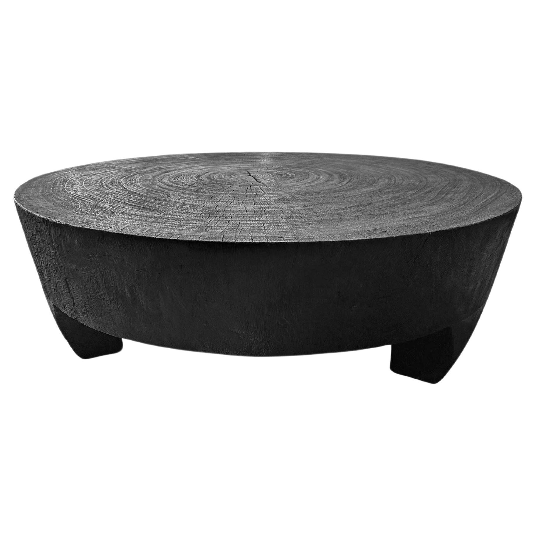 Tavolo rotondo scultoreo in legno massiccio di Suar, finitura bruciata, organico moderno