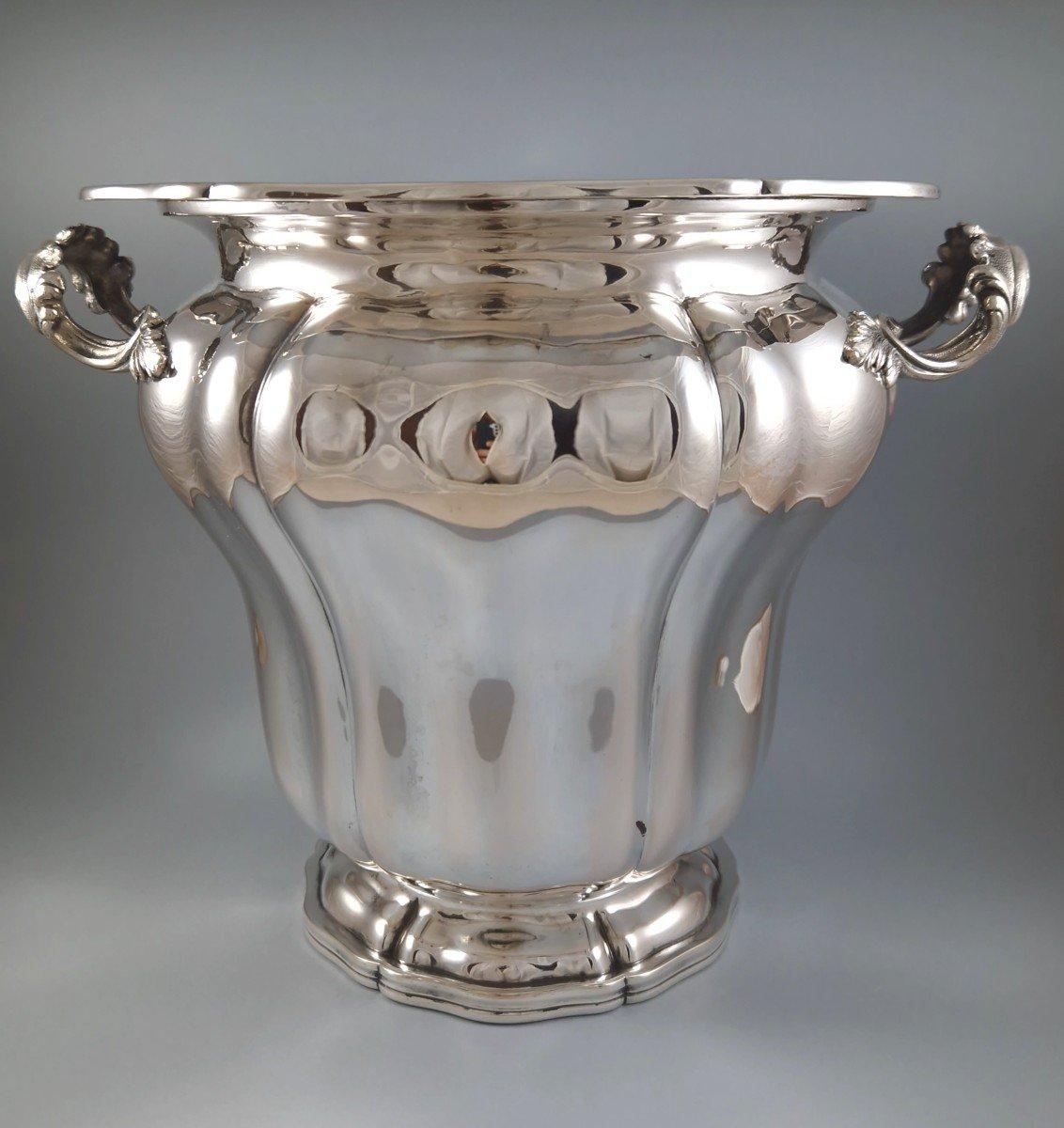 Large champagne ice bucket on foot in Solid Silver 

The base, the body and the polylobed neck, the grips decorated with foliage 

800 silver hallmark 

Measures: Height: 23.4 cm 
Diameter: 23.7 cm 
Length with the grips: 28.5 cm 
Weight: