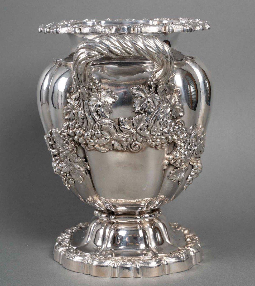 Solid silver cooler in the “Medici” shape, the round scalloped base is decorated with arabesques and flowers forming a pedestal on which is placed the ovoid vase with melon ribs, entirely decorated in applique with foliage and bunches of grapes