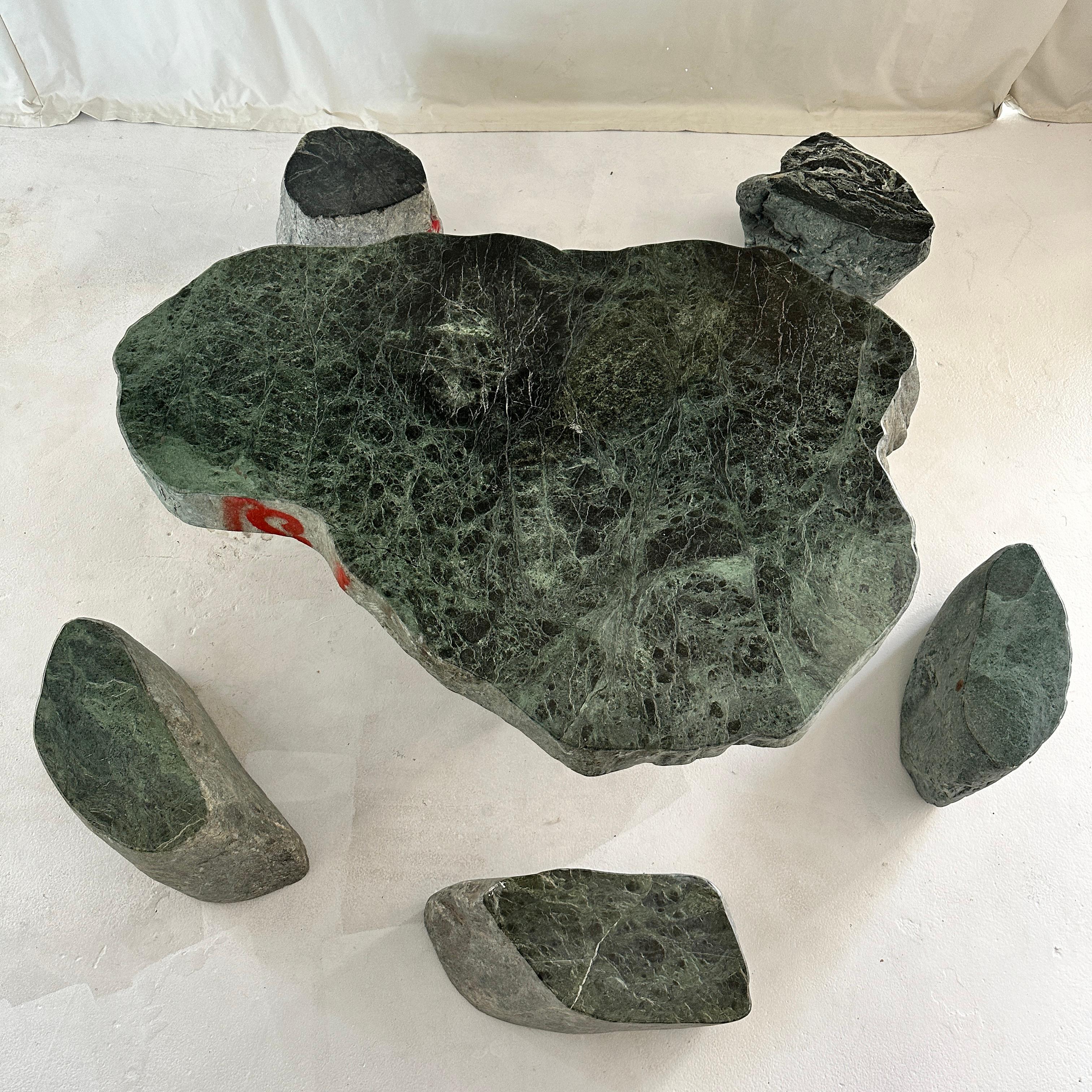 Monumentaler Teetisch aus massivem Speckstein mit fünf passenden Hockern, in den 1980er Jahren aus China importiert. Jedes Stück wird von Hand aus massiven Blöcken tiefgrünen Steins gemeißelt, was ihm eine ebenso skulpturale wie elementare Präsenz