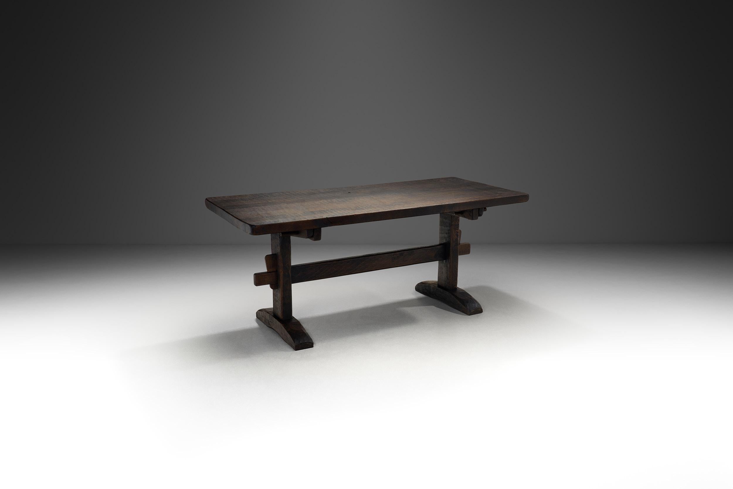 Crafted in the mid-20th century, this table appears to be designed in line with the Brutalist movement, with the style’s basic characteristics all presenti: unornamented, solid wood, exposed joints, and raw wooden surfaces. The architectural style