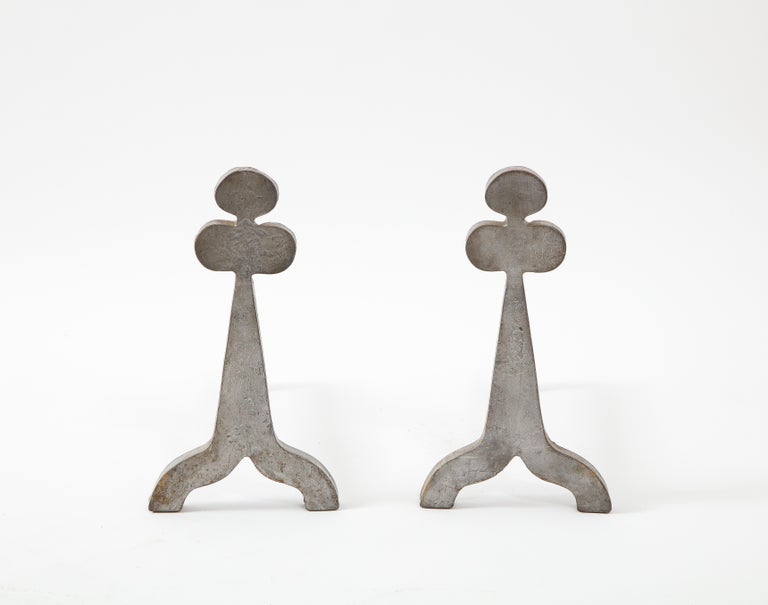 Large and heavy solid steel andirons cut in the shape of a clover.
