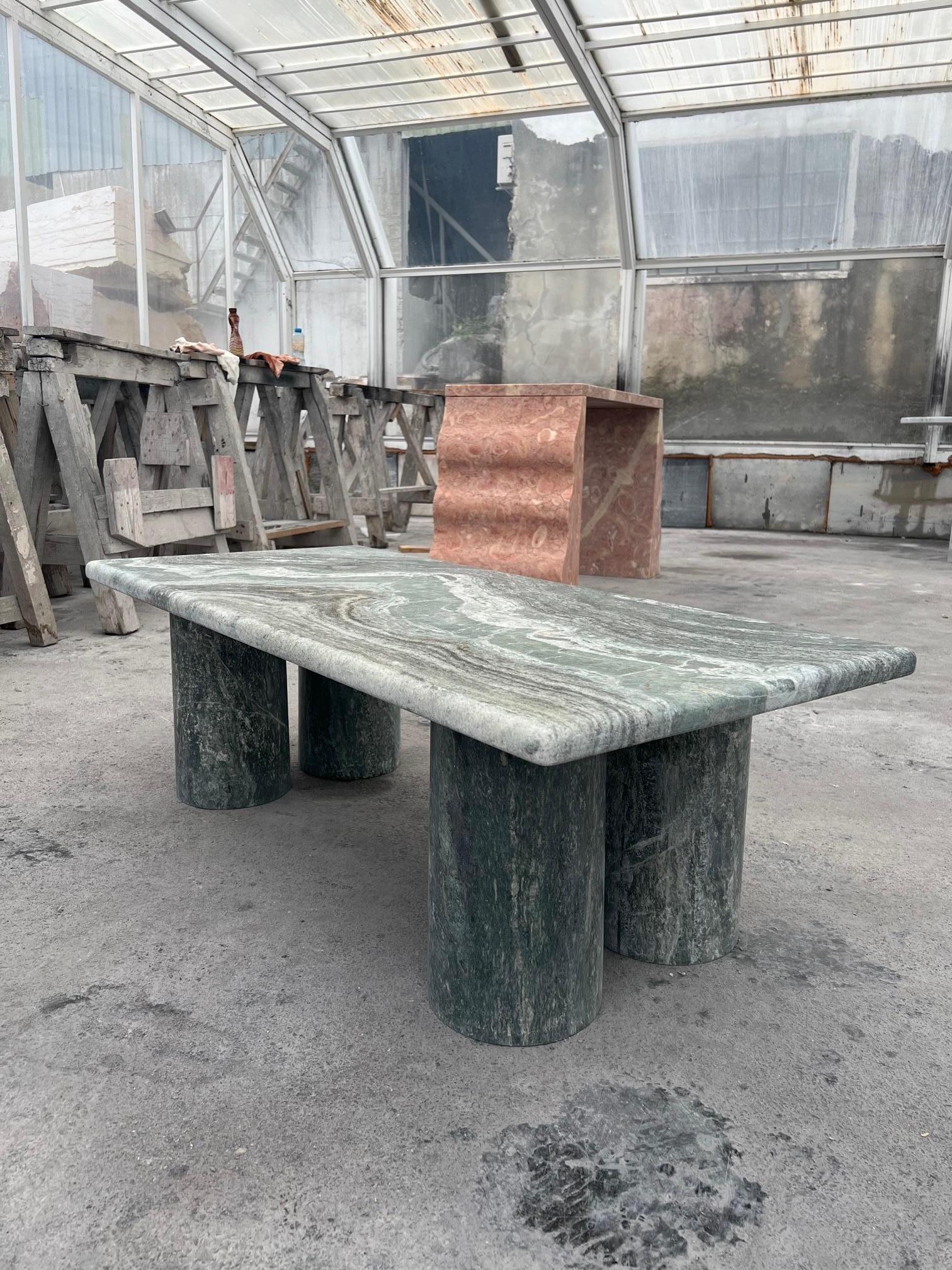 This minimalist Green marble coffee table is made from one material, featuring a curved edge top in green marble with white veining that elegantly sits on four cylindrical columns. 

Sophisticated and timeless, the coffee table draws inspiration