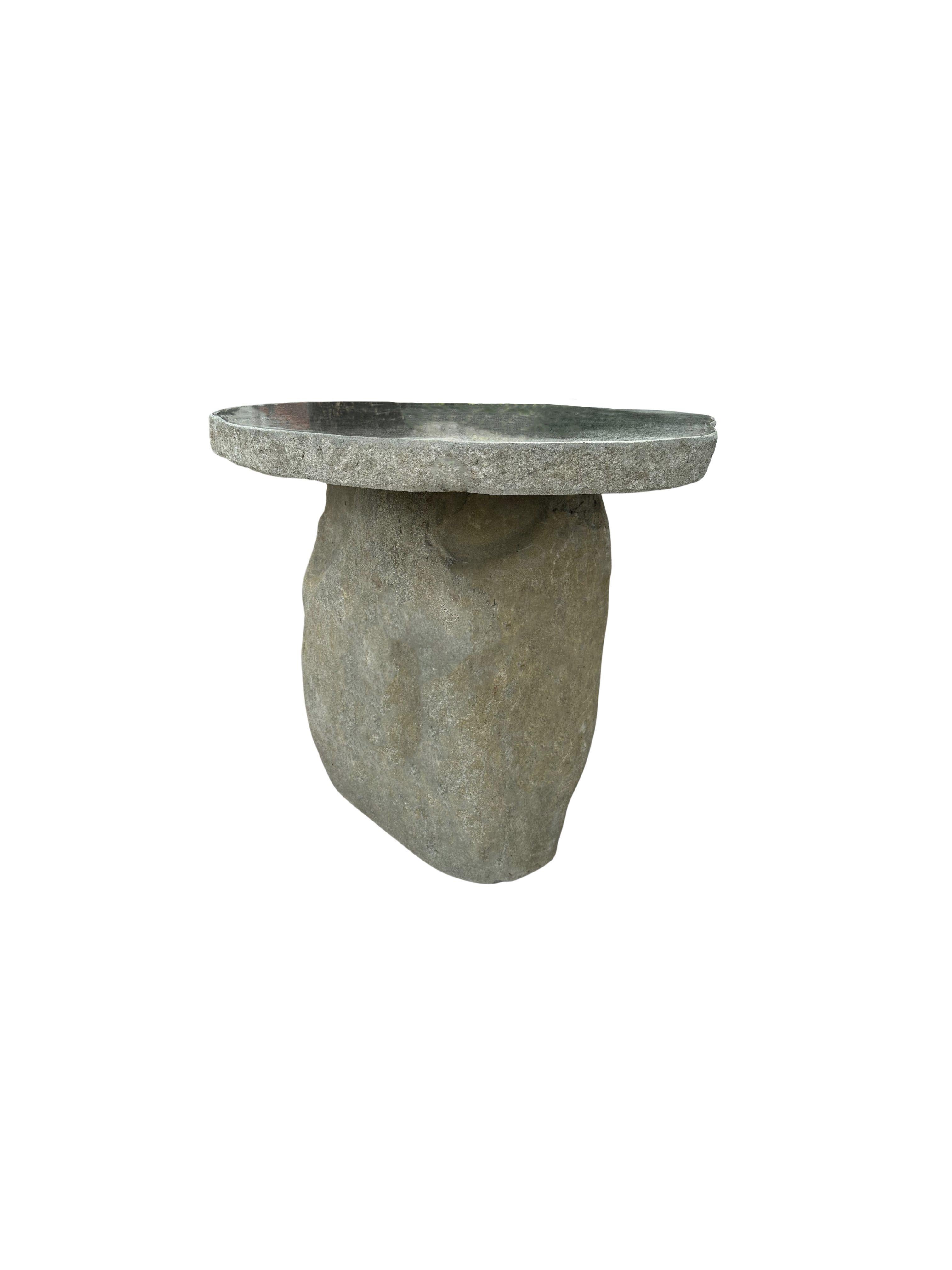 A incredibly heavy and solid rounded stone table. This lovely sculptural object was crafted from 2 solid stones sourced from a river bed in East Java. A raw and organic object with beautiful textures. Its top side was cut, sanded down and polished