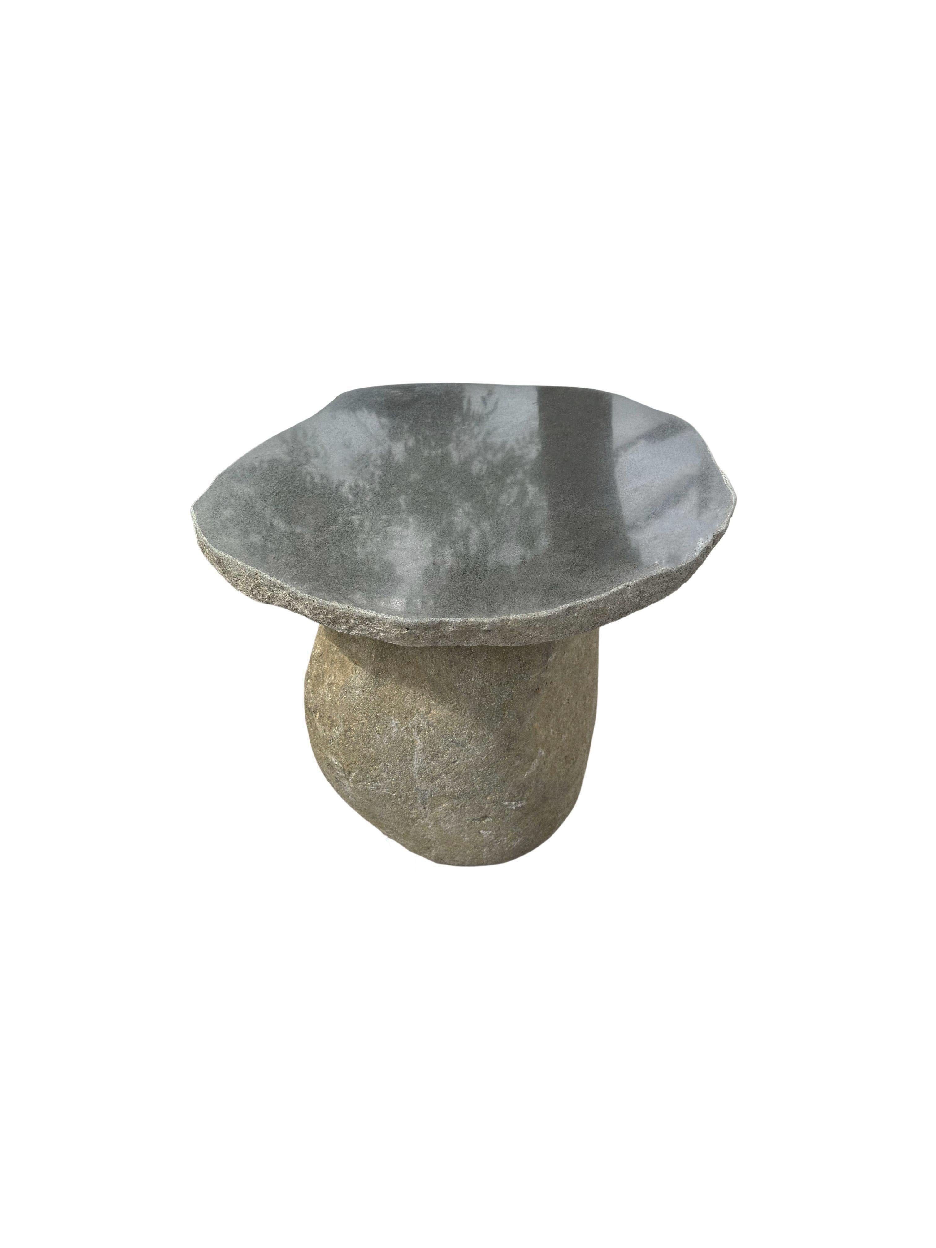 A incredibly heavy and solid rounded stone table. This lovely sculptural object was crafted from 2 solid stones sourced from a river bed in East Java. A raw and organic object with beautiful textures. Its top side was cut, sanded down and polished