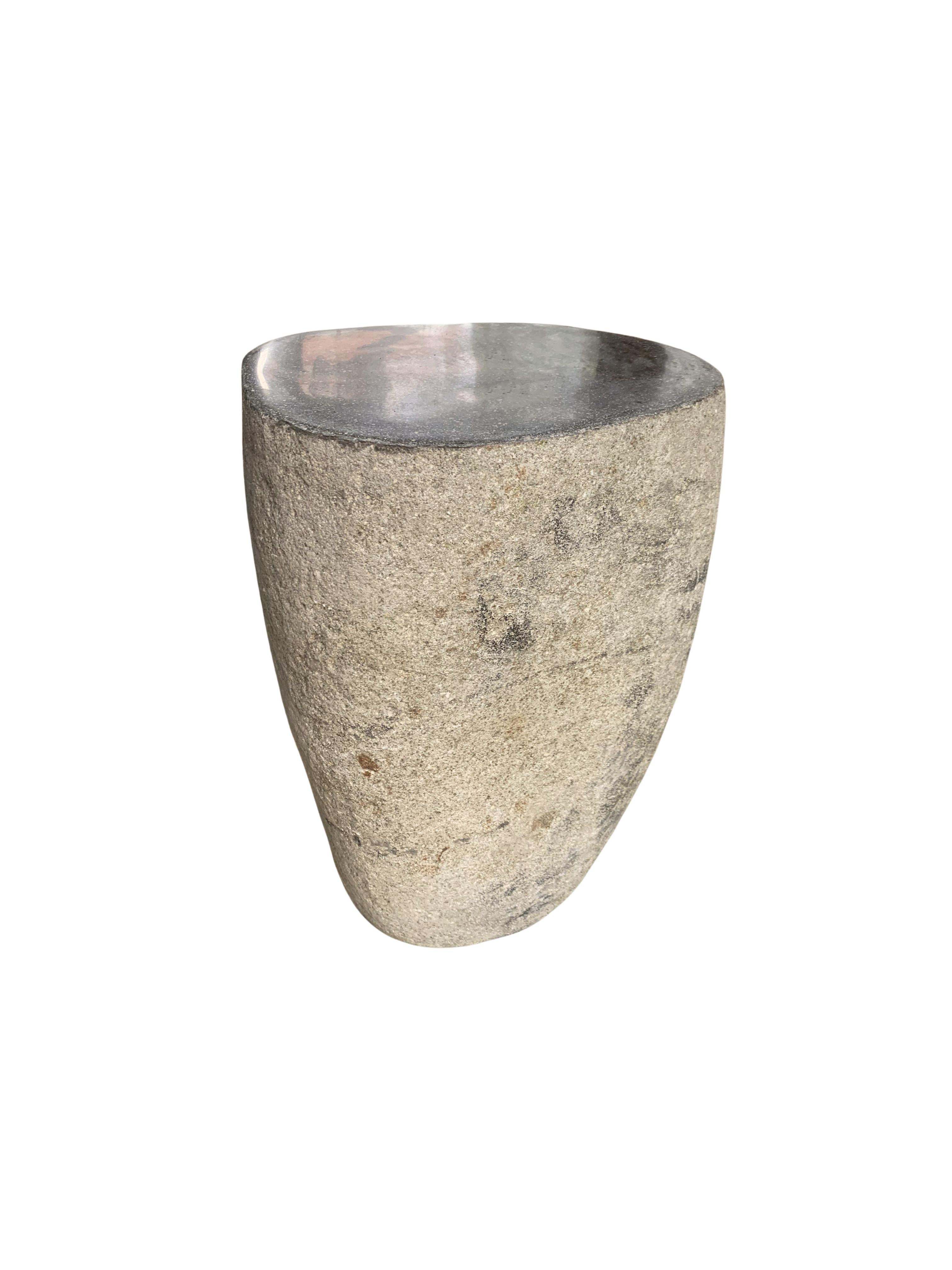 A incredibly heavy and solid rounded stone side table / pedestal. This lovely sculptural object was crafted from a solid stone sourced from a river bed in East Java. A raw and organic object with beautiful textures. Its top side was carved, sanded