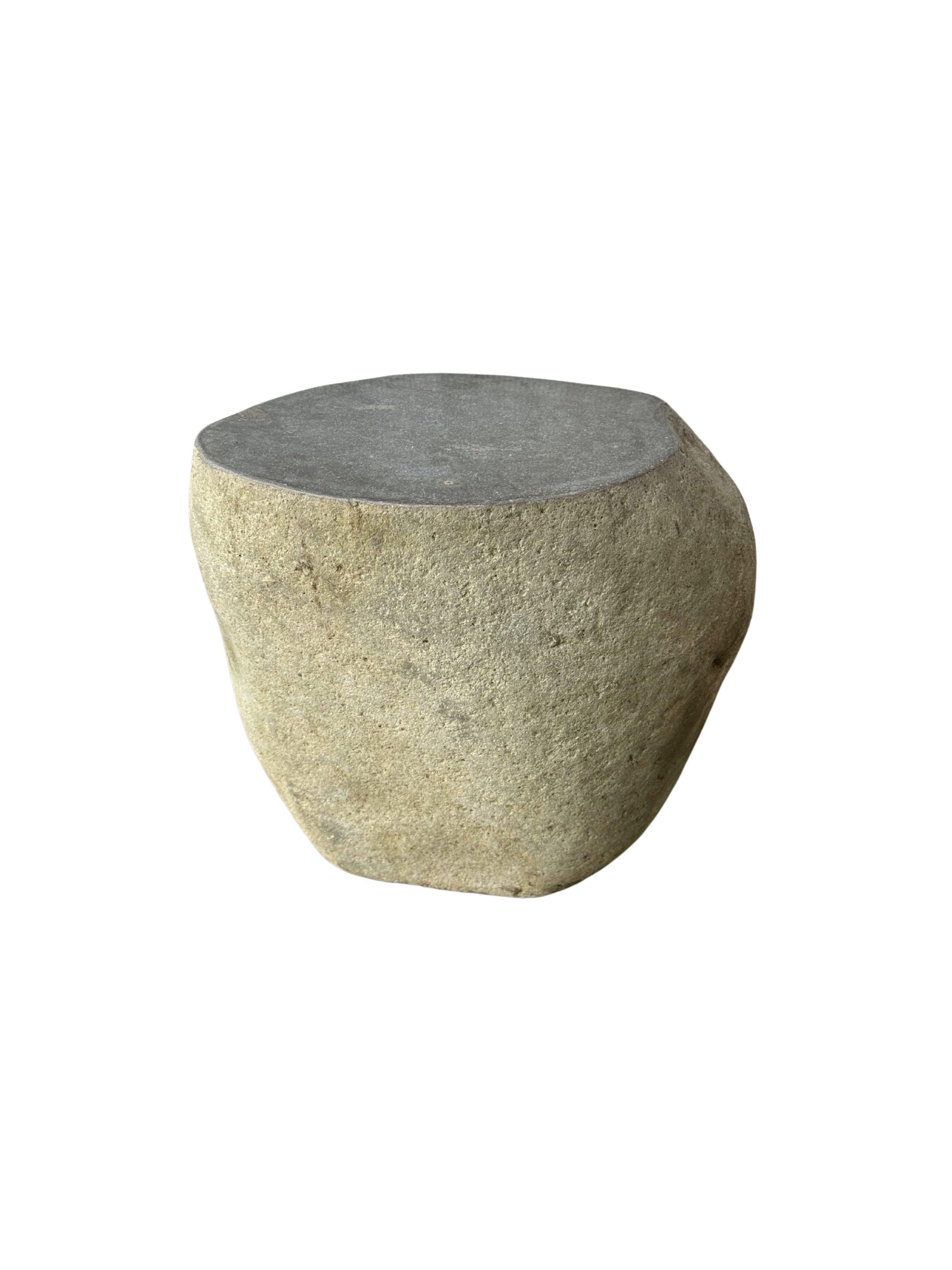 A incredibly heavy and solid rounded stone side table / pedestal. This lovely sculptural object was crafted from a solid stone sourced from a river bed in East Java. A raw and organic object with beautiful textures. Its top side was carved, sanded