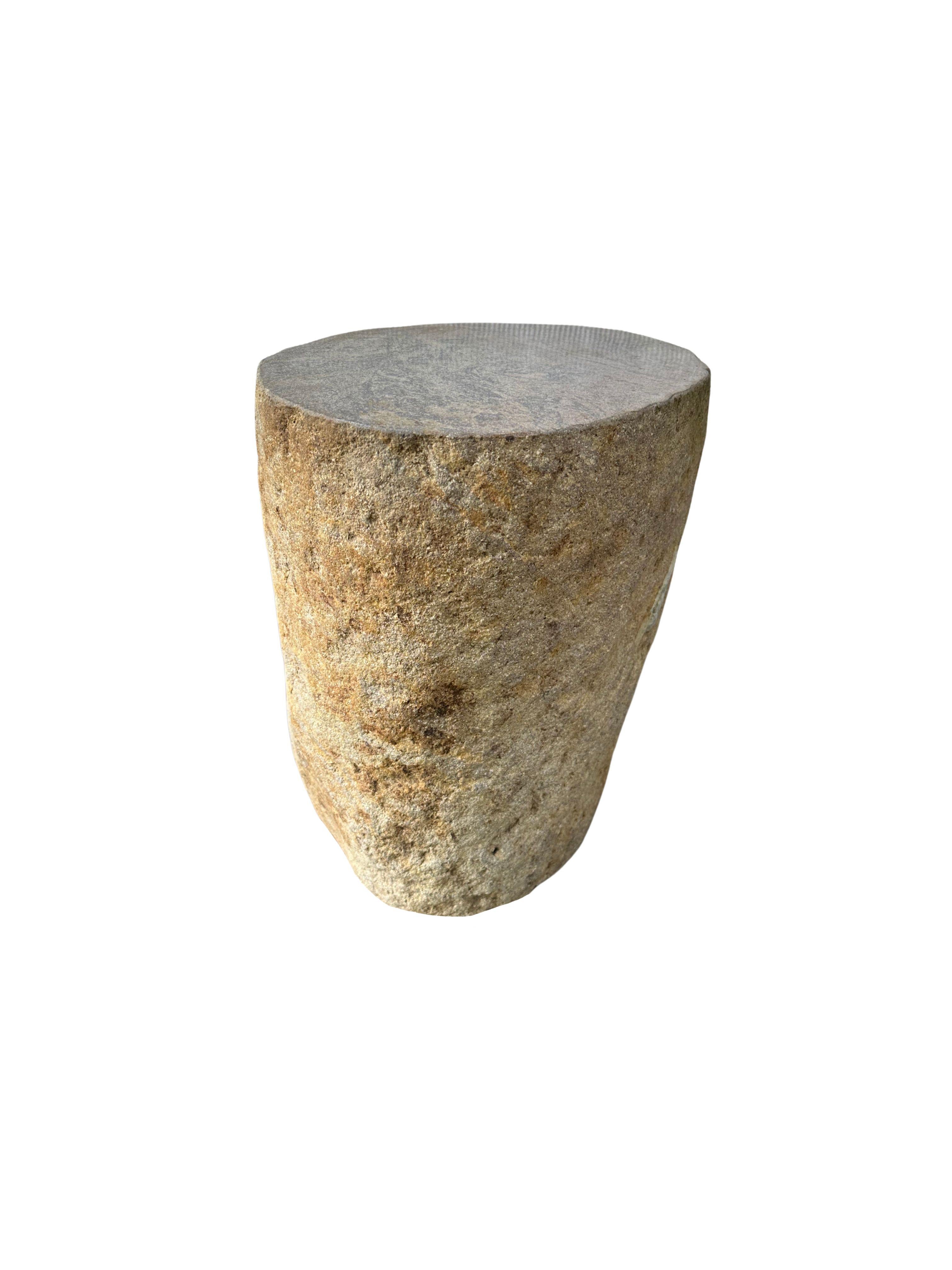 A incredibly heavy and solid rounded stone side table / pedestal. This lovely sculptural object was crafted from a solid stone sourced from a river bed in East Java. A raw and organic object with beautiful textures. Its top side was carved, sanded