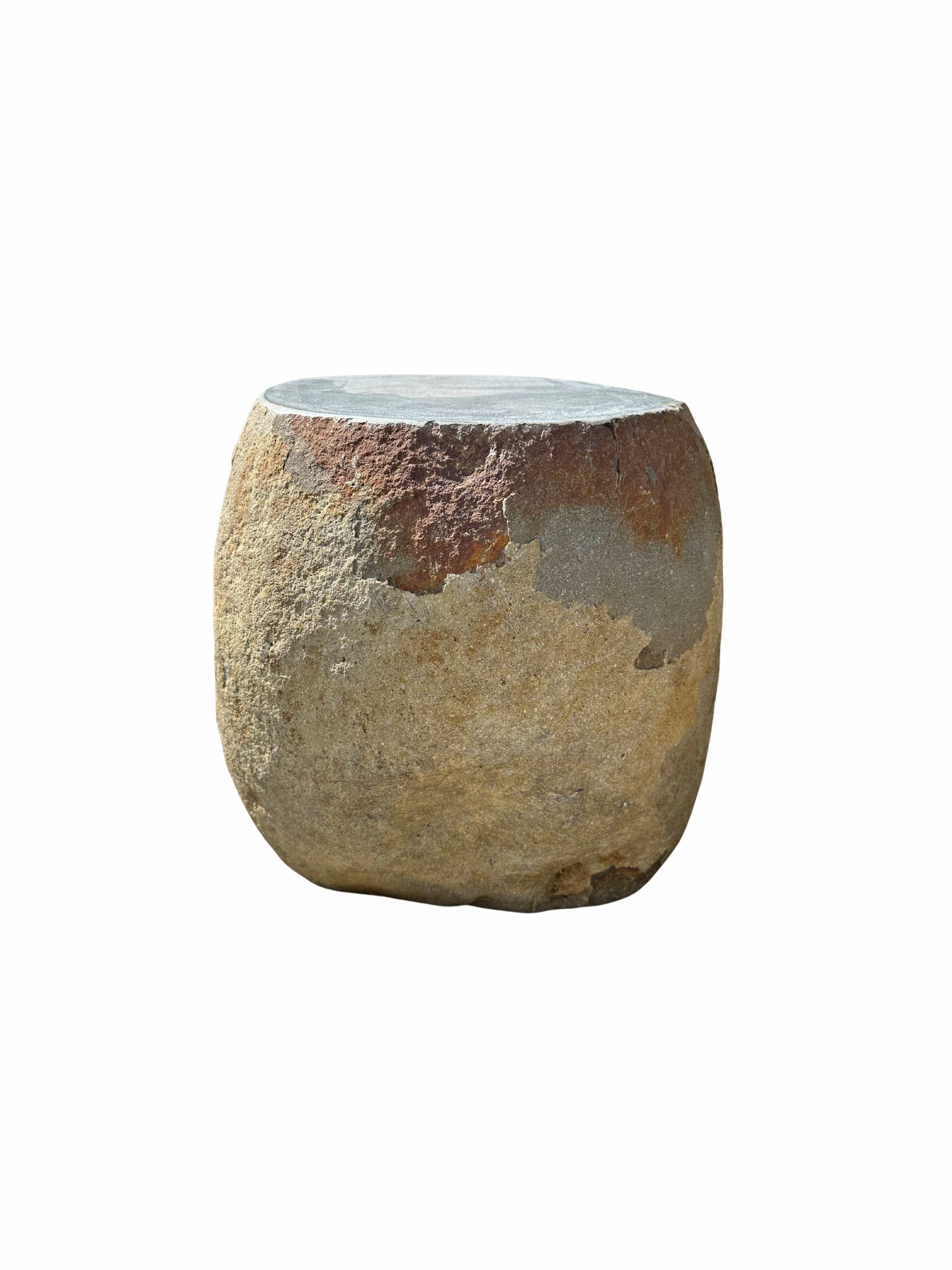 A incredibly heavy and solid rounded stone side table / pedestal. This lovely sculptural object was crafted from a solid stone sourced from a river bed in East Java. A raw and organic object with beautiful textures. Its top side was carved, sanded