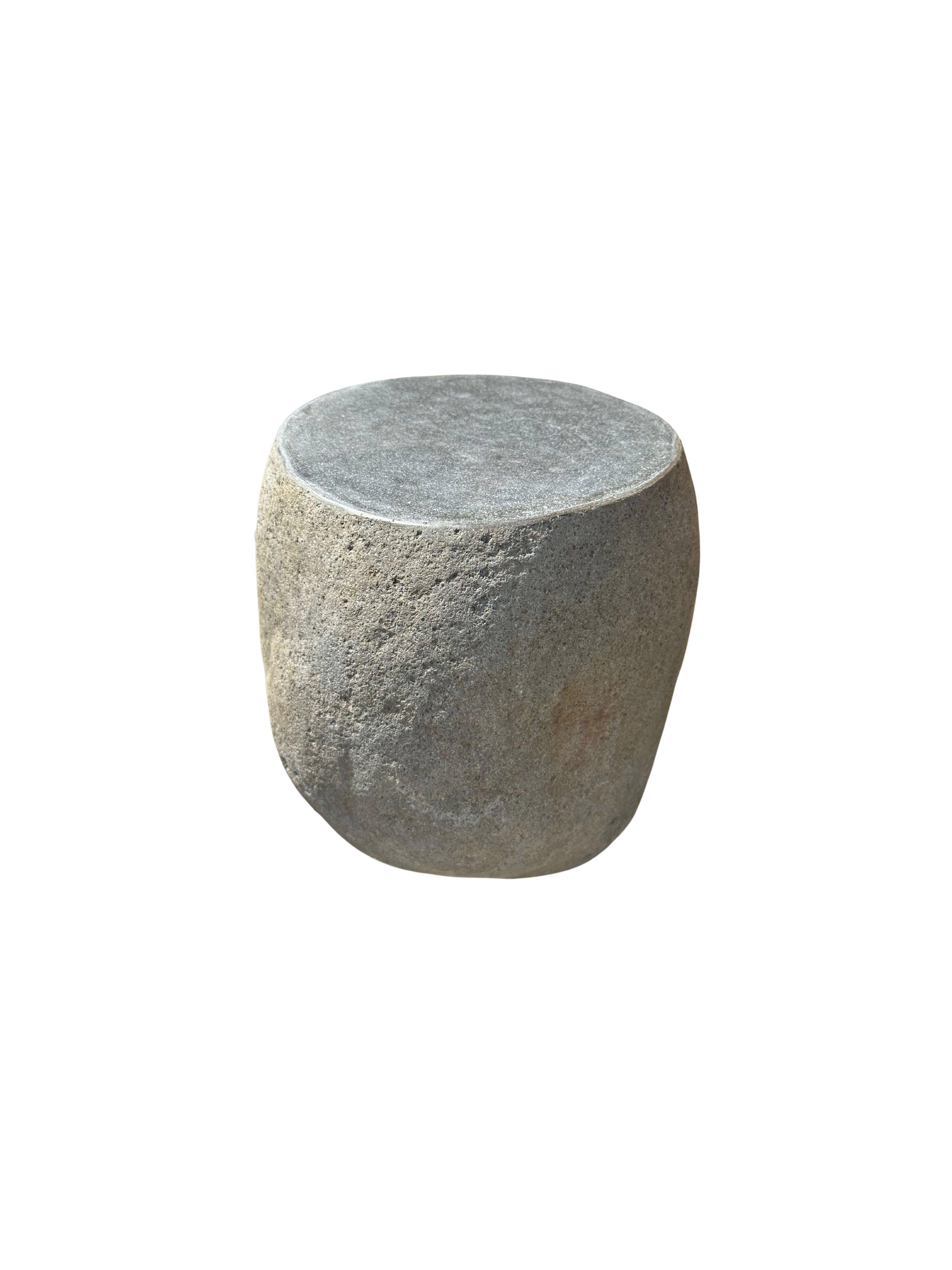 A incredibly heavy and solid rounded stone side table / pedestal. This lovely sculptural object was crafted from a solid stone sourced from a river bed in East Java. A raw and organic object with beautiful textures. Its top side was carved, sanded