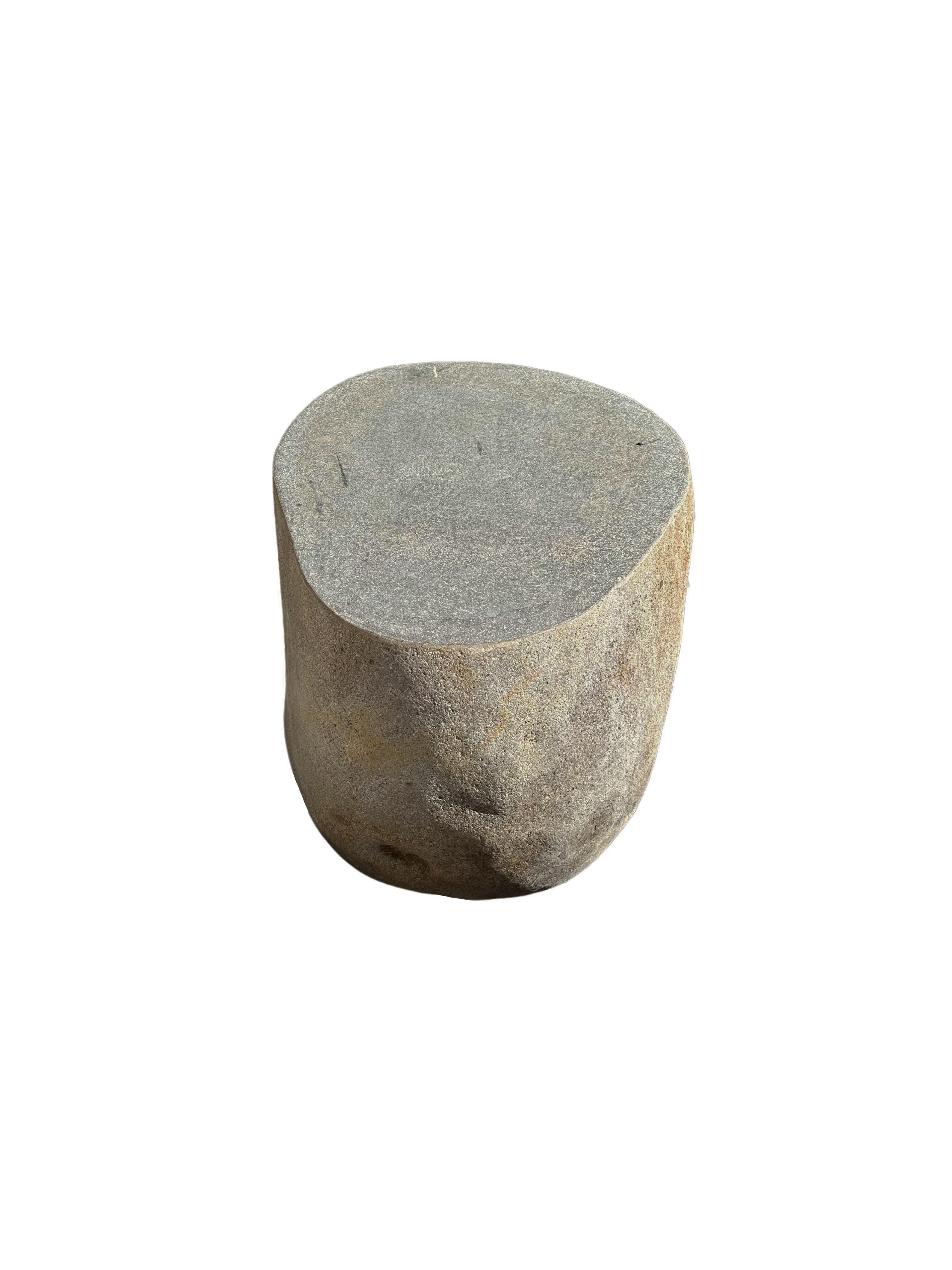 A incredibly heavy and solid rounded stone side table / pedestal. This lovely sculptural object was crafted from a solid stone sourced from a river bed in East Java. A raw and organic object with beautiful textures. Its top side was carved, sanded