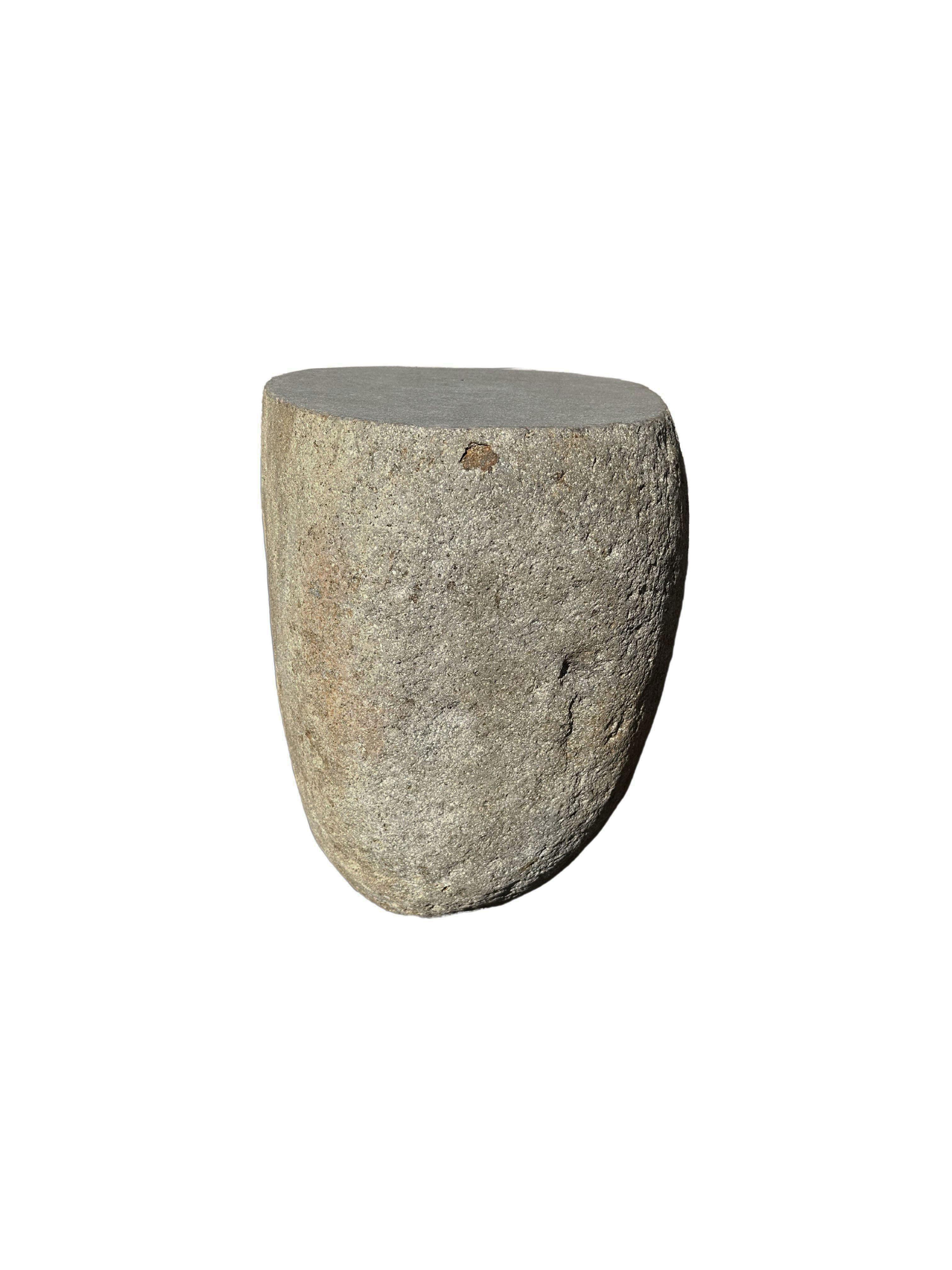 A incredibly heavy and solid rounded stone side table / pedestal. This lovely sculptural object was crafted from a solid stone sourced from a river bed in East Java. A raw and organic object with beautiful textures. Its top side was carved, sanded