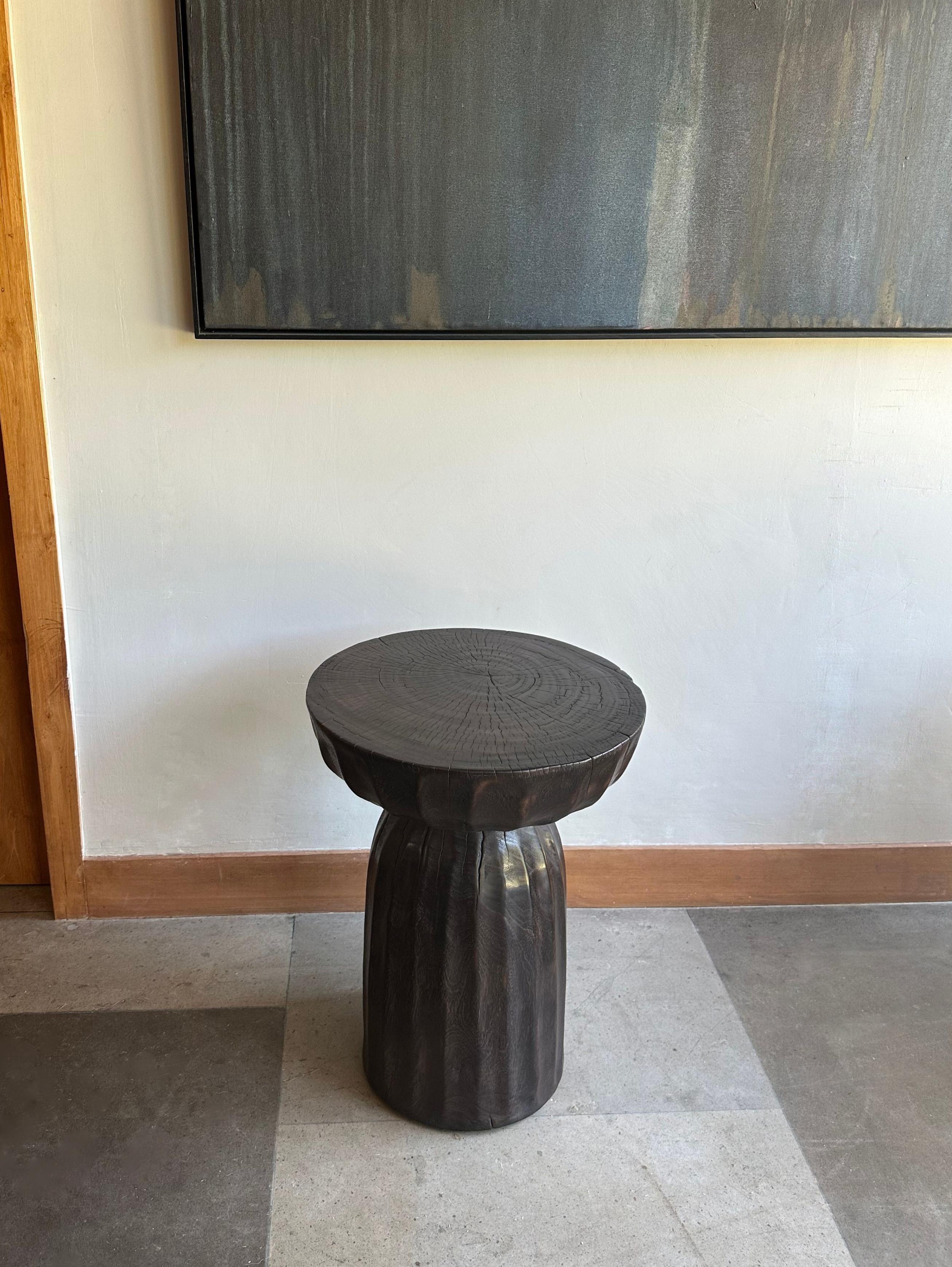 A wonderfully sculptural round side table, with an hourglass shape. Its neutral pigments make it perfect for any space. A uniquely sculptural and versatile piece certain to invoke conversation. It was crafted from a solid block of mango wood and has
