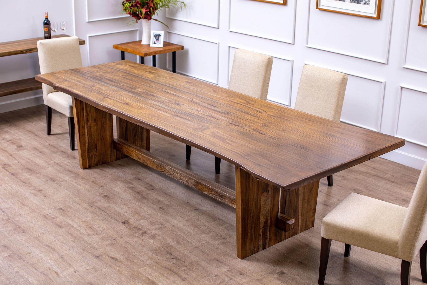 This is a truly unique piece of functional art, book-matching two pieces of live edge teak to create a dining table that is the focal point of the home. Expertly crafted out of 100% solid Burmese teak, this table has beams that penetrate the legs