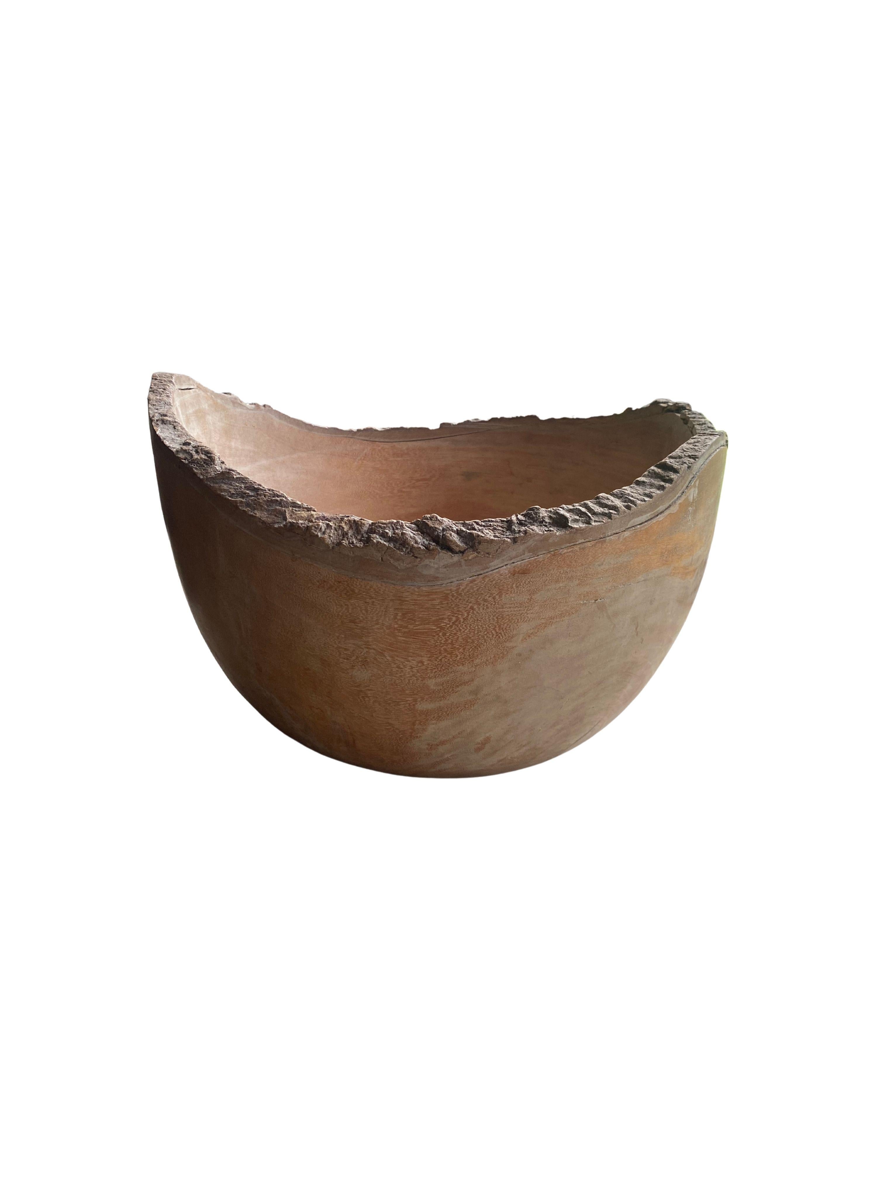 A solid teak wood bowl crafted on the island of Java from a slab of burl wood.The bowl was cut from a much larger slab of wood and maintains a minimalist organic design with a range of textures. The rim still bears the outer textures of the tree.