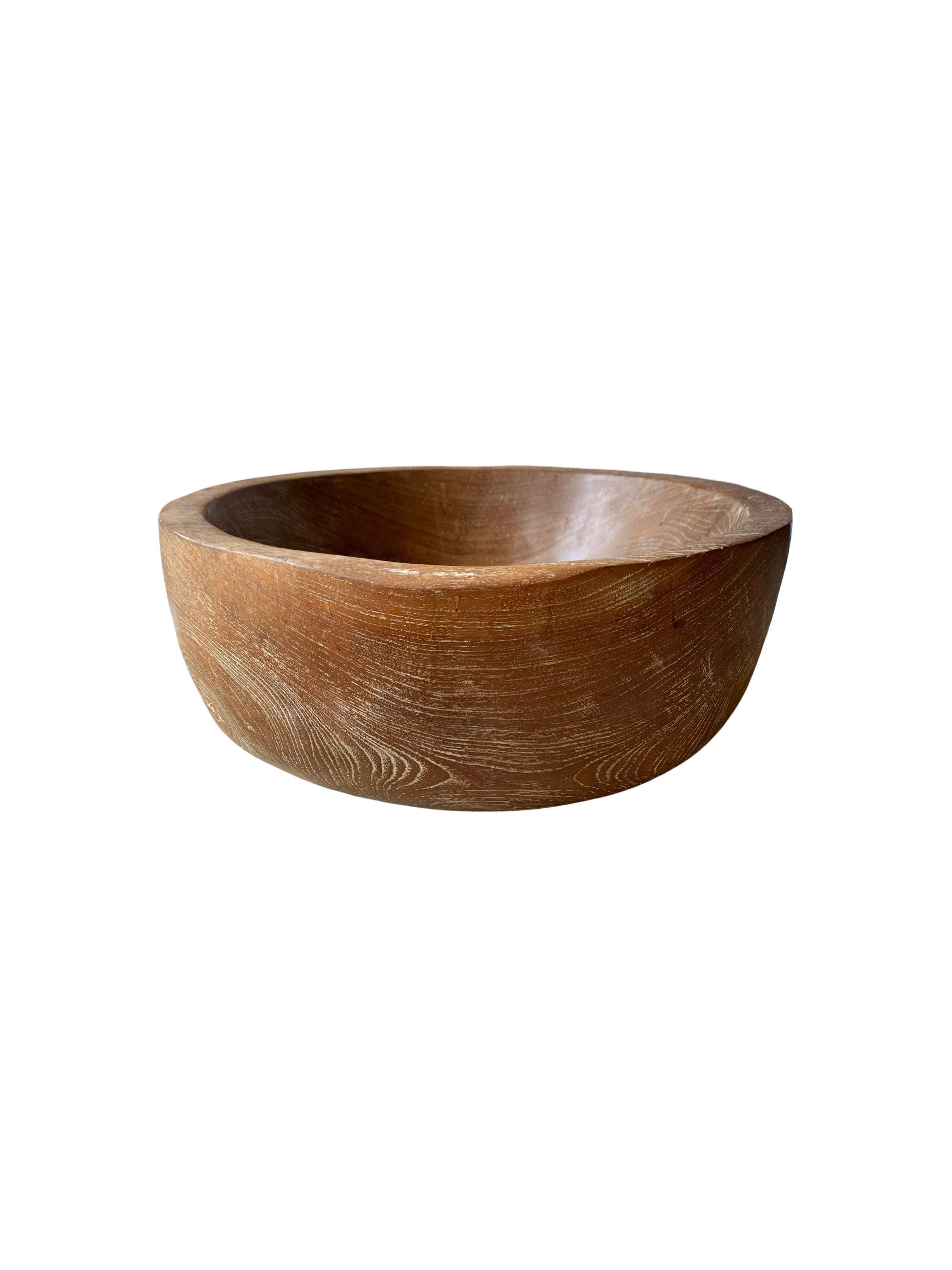 A solid teak wood bowl crafted on the island of Java from a slab of teak wood.cThe bowl was cut from a much larger slab of wood and maintains a minimalist organic design with a range of textures. Perfect to display items as a centrepiece or