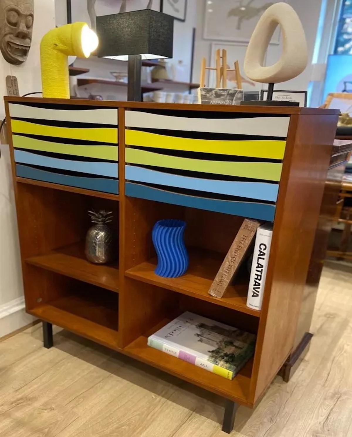 A vintage mid 20th century Teak shelving unit with filing drawers attributed to Arne Vodder. 

This shelving unit features colourful pops of colour on the filing drawer fronts and wide open shelving for display or extra storage space. 

A solid high