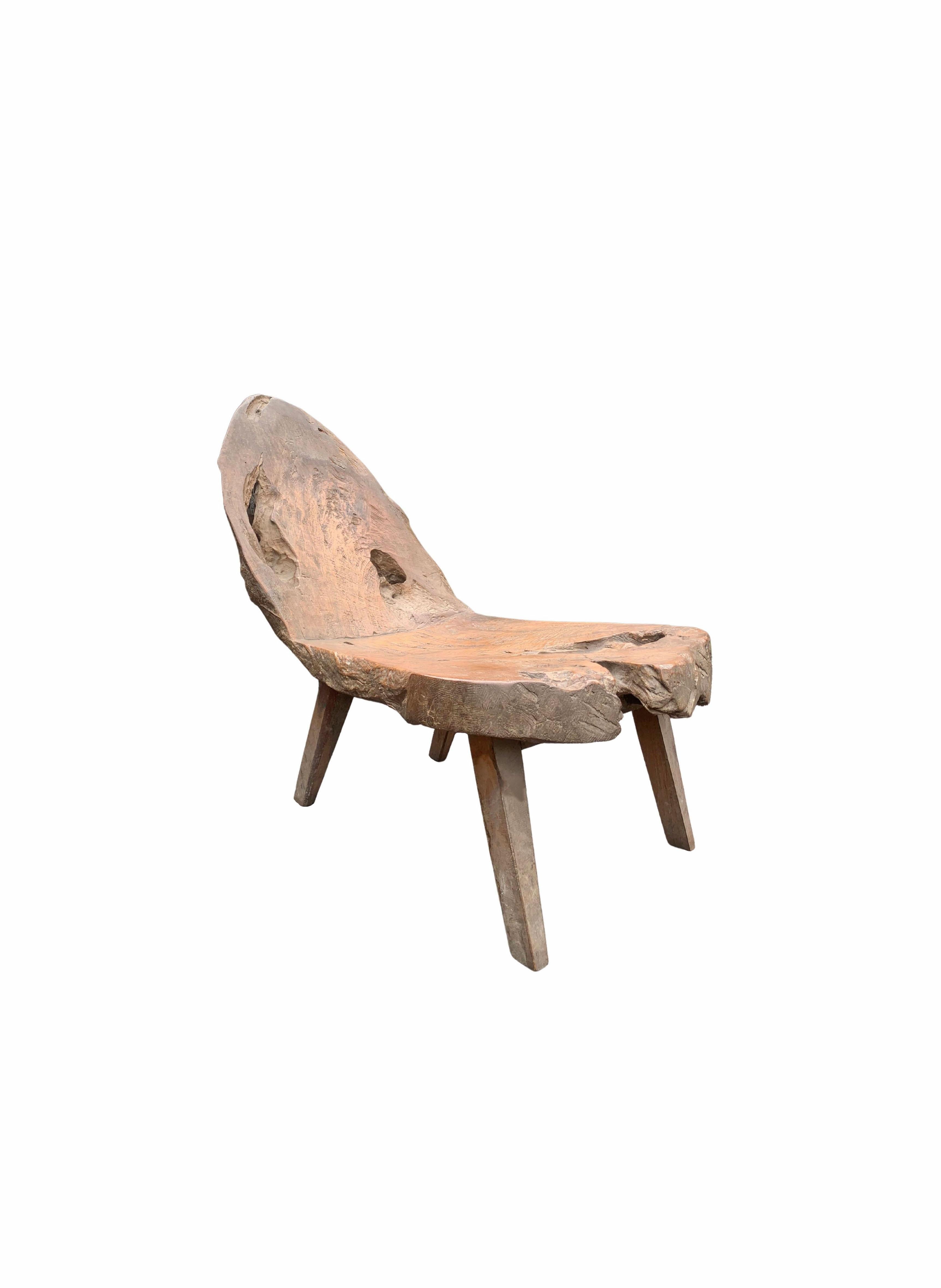 Cette chaise en teck sculptée à la main provient de l'île de Madura, au large de la côte nord-est de Java. Il présente une merveilleuse forme organique avec des pieds angulaires. Le mélange de textures, de formes et de trous ajoute à son charme.