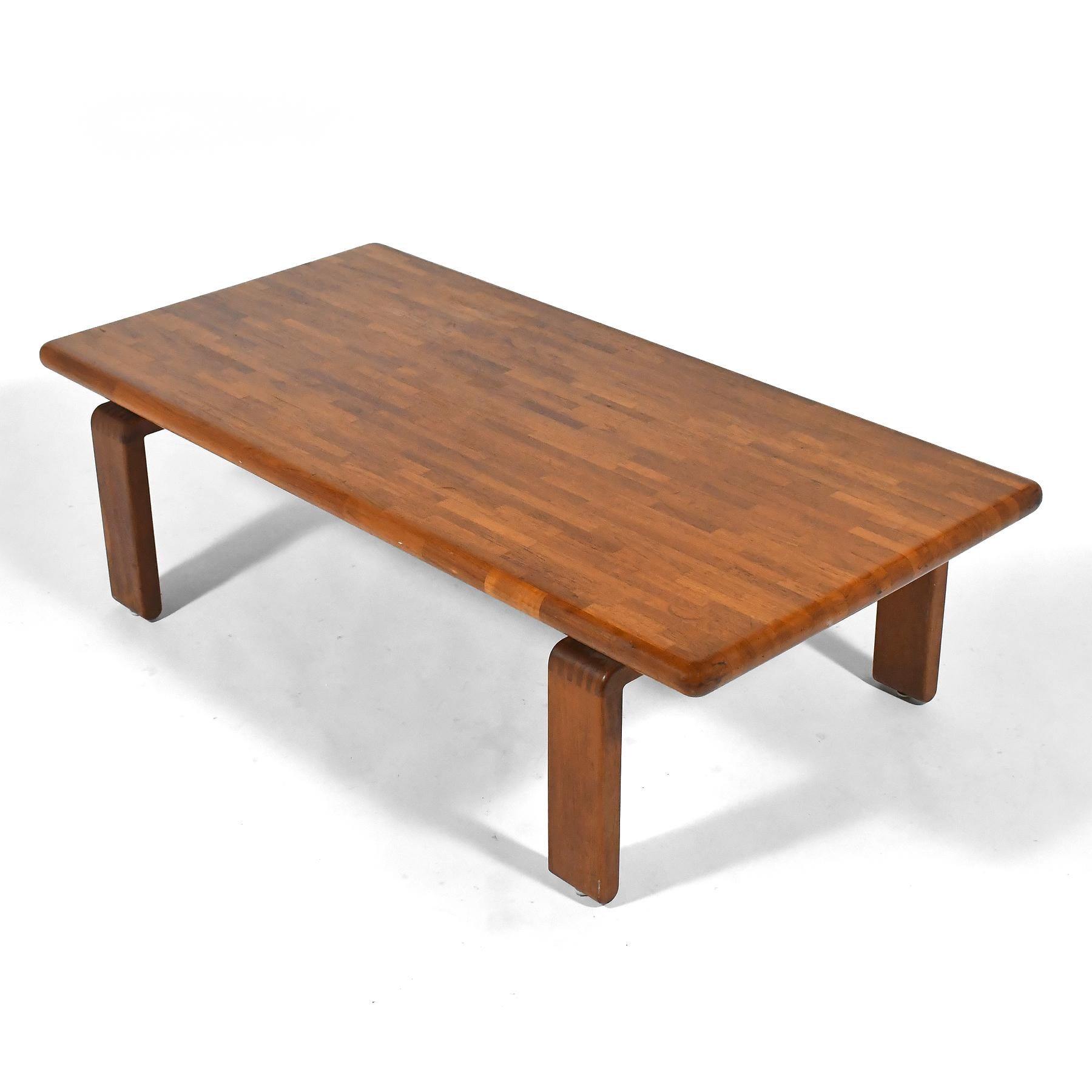 Cette extraordinaire table basse scandinave est fabriquée en teck massif. La forme discrète présente un certain nombre de détails remarquables : le plateau est fabriqué à partir de bandes de bois stratifié et présente un bord arrondi qui met en