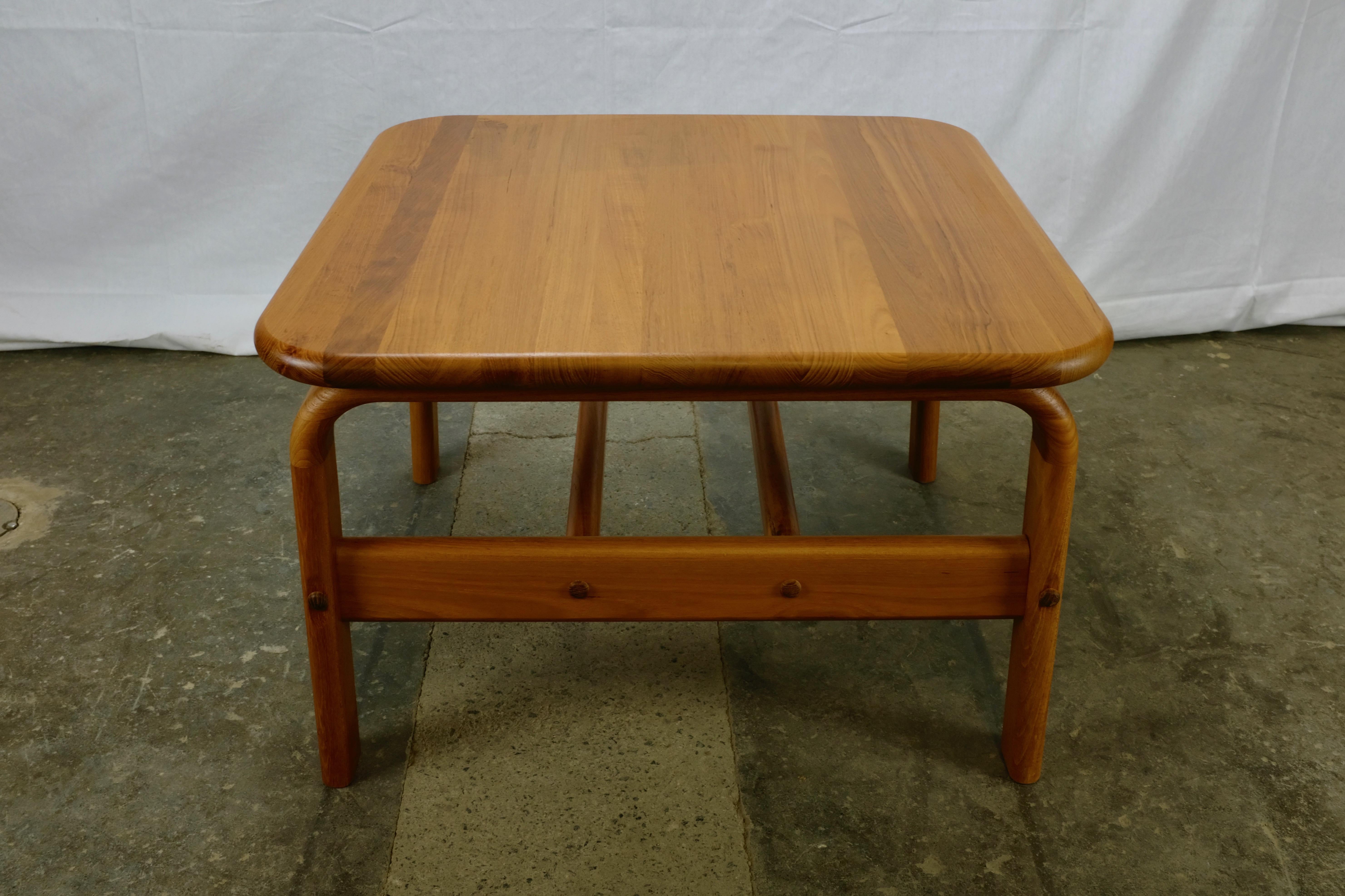 Danish-made coffee table featuring a solid teak top and sturdy legs and frame. 

The frame is constructed so that the legs appear to arch upwards to support the top. A bullnose profile on all edges lends a hint of softness to the table and also