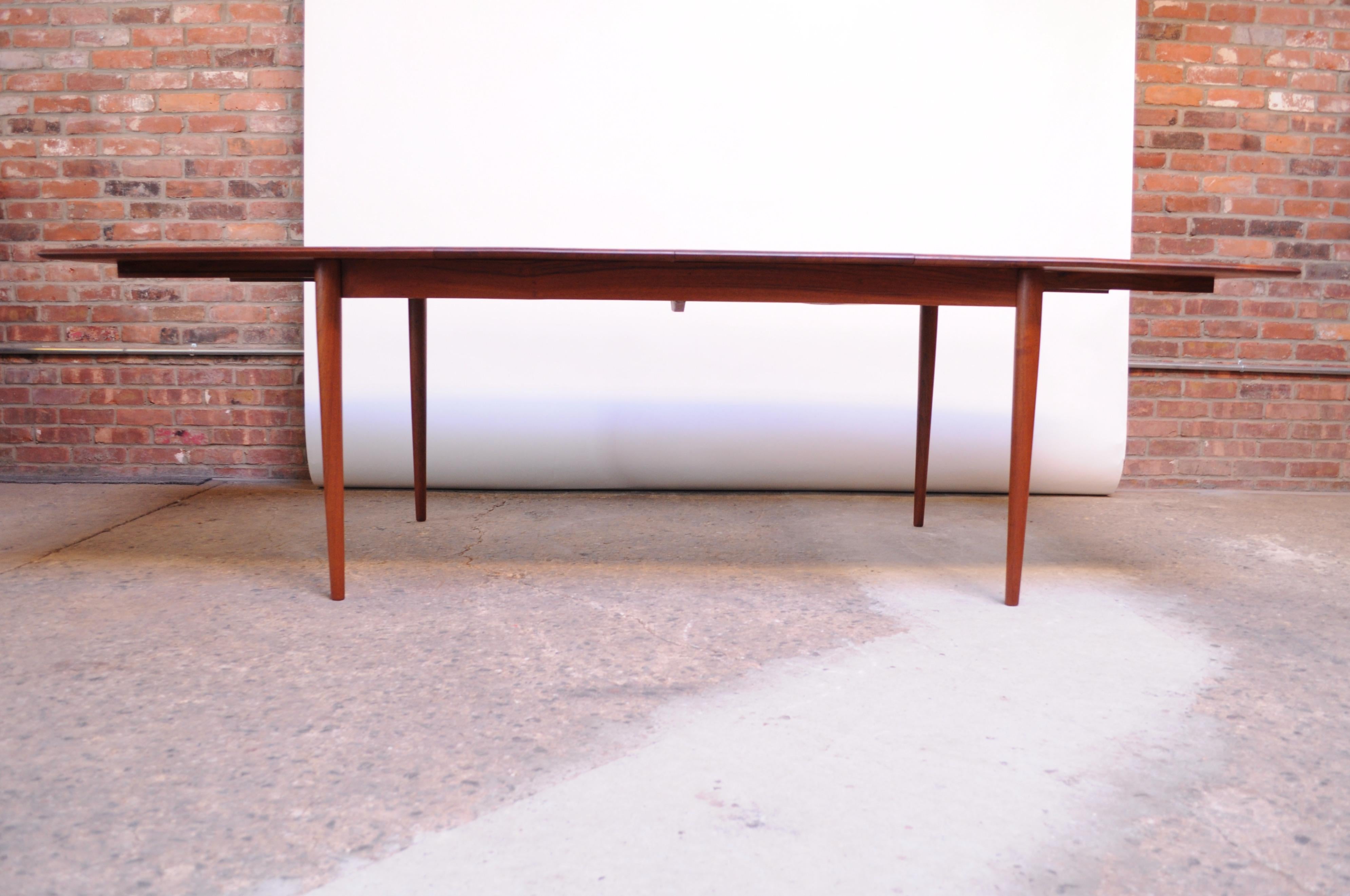 Solid teak extendable dining table by Johannes Aasbjerg for Excellent Furniture Company (circa 1963 Denmark).
Unparalleled quality, composed of solid teak planks with vivid grain and rich color. Includes two additional 18.25