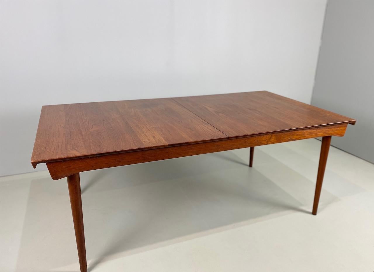 This extendable table designed by Finn Juhl is made of solid teak and combines elegant forms with practical functions. Two teak leafs stow beneath the table. The sculptural lips at both ends of the table are handles to open and close it. Measure:
