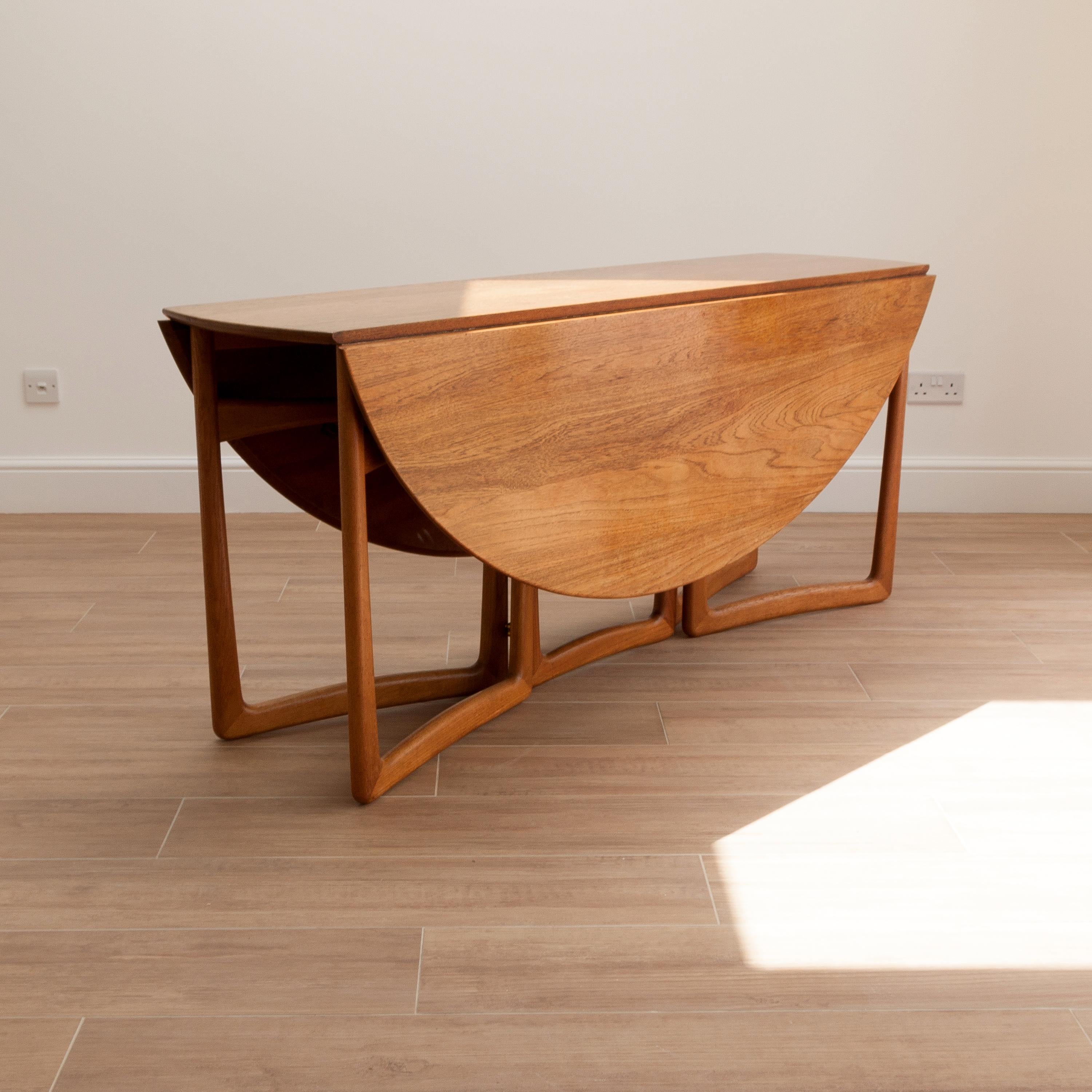 A fabulous Hvidt and Mølgaard-Nielsen drop leaf table in solid teak with brass ball hinges. The sculptural legs fold away to allow the leaves to drop. Beautiful detail to the brass hinges. This table is an iconic example of Hvidt and