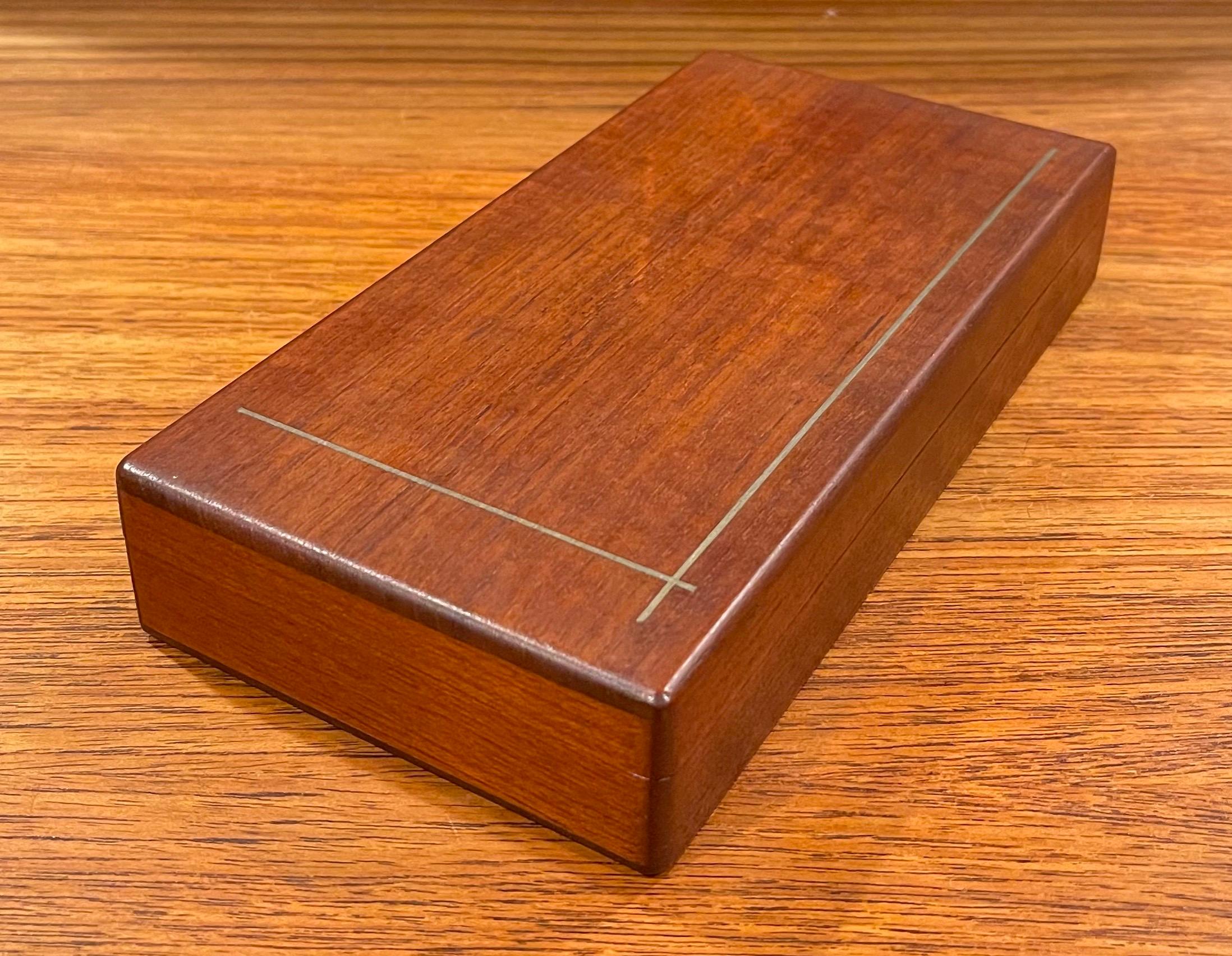A very rare and hard to find solid teak inlaid jewelry or trinket box by Maison Gourmet of Denmark, circa 1950s. The box has a removable lid with a fine brass inlay and the inside is coated in cork; the piece measures: 8.5