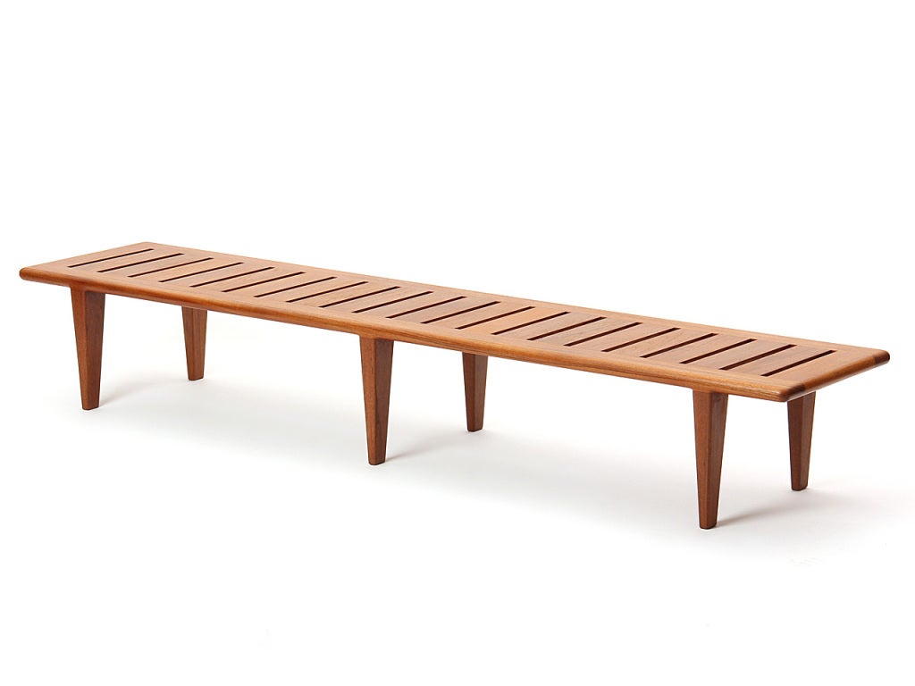 A midcentury solid teak bench with a slatted seat over six (6) tapered legs.
Designed by Hans Wegner and made by Johannes Hansen in Denmark, 1950s.