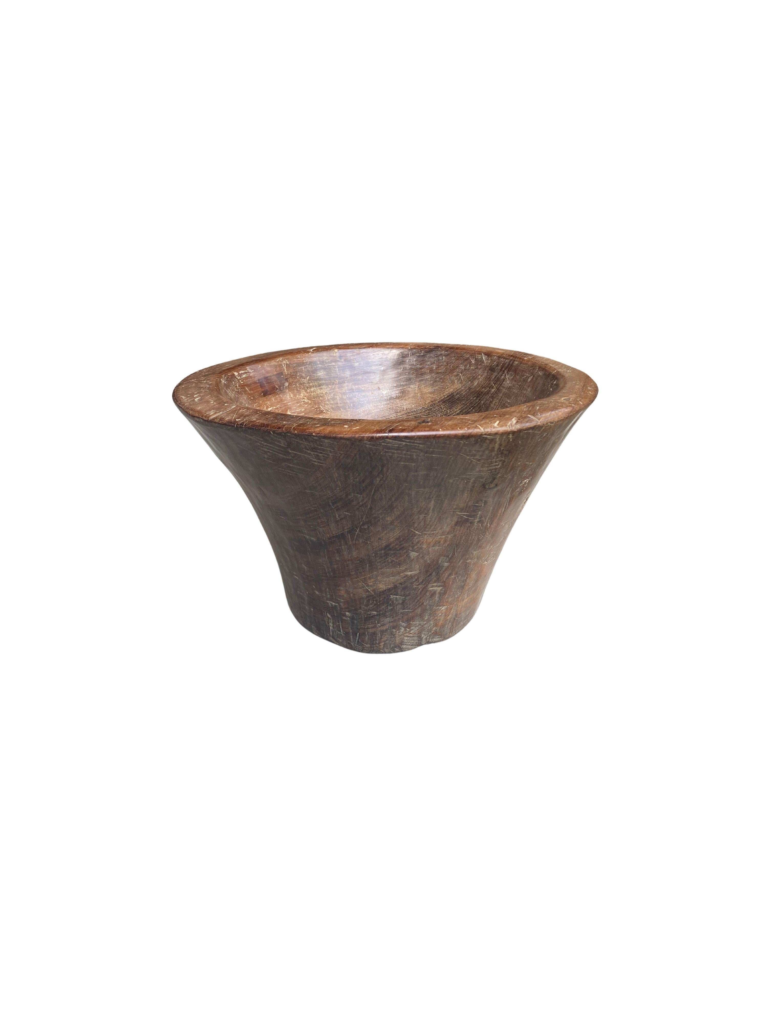 A solid teak wood bowl crafted on the island of Java. The bowl was cut from a much larger slab of wood and maintains a minimalist organic design with a range of textures. Perfect to display items as a centrepiece or decorative addition to any