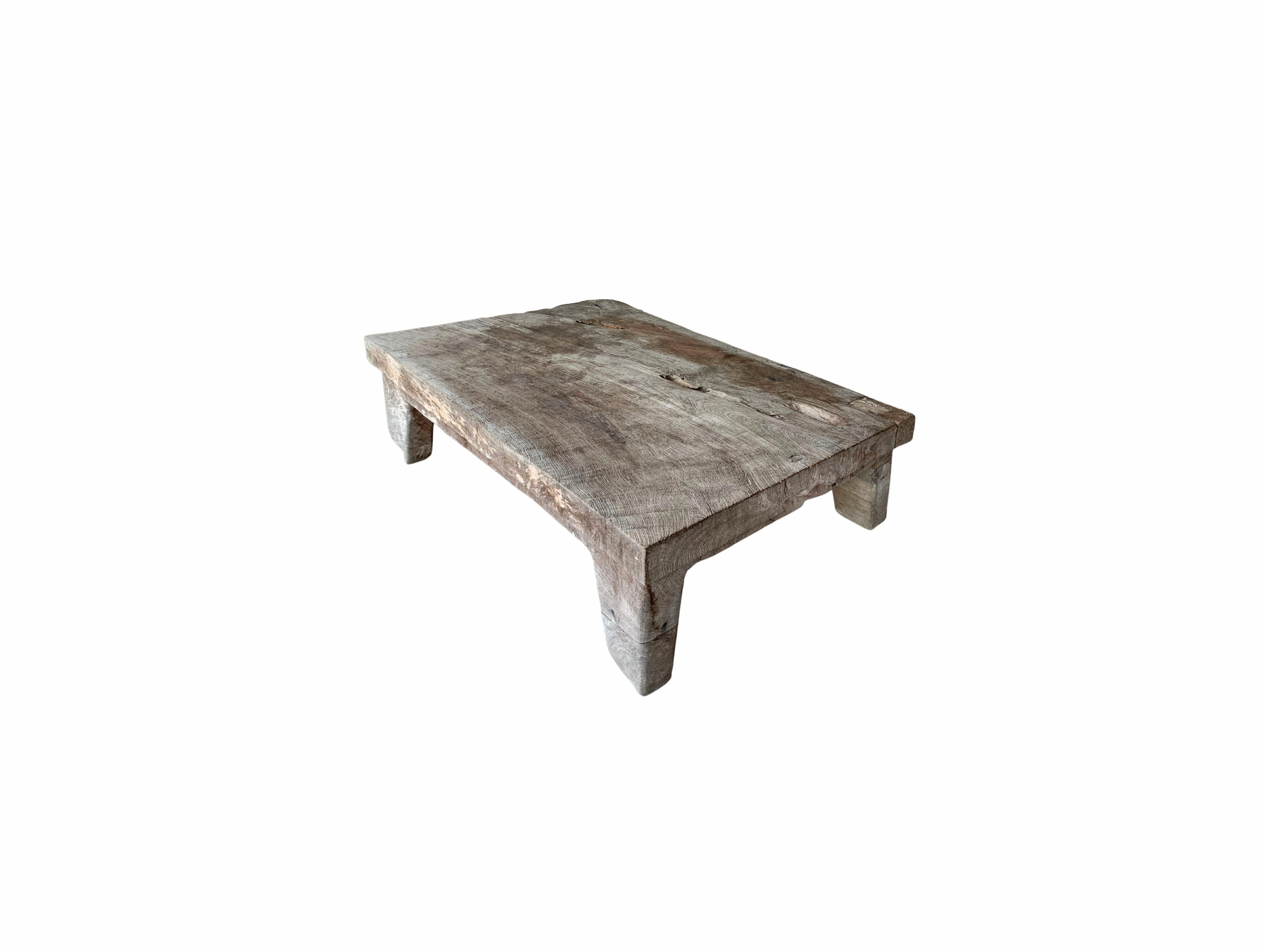 This solid teak coffee table was crafted on the island of Madura off the Northeastern coast of Java, Indonesia. It features angular legs that follow the curvature of each corner. A wonderful addition to any space. The fading of the wood, age-related
