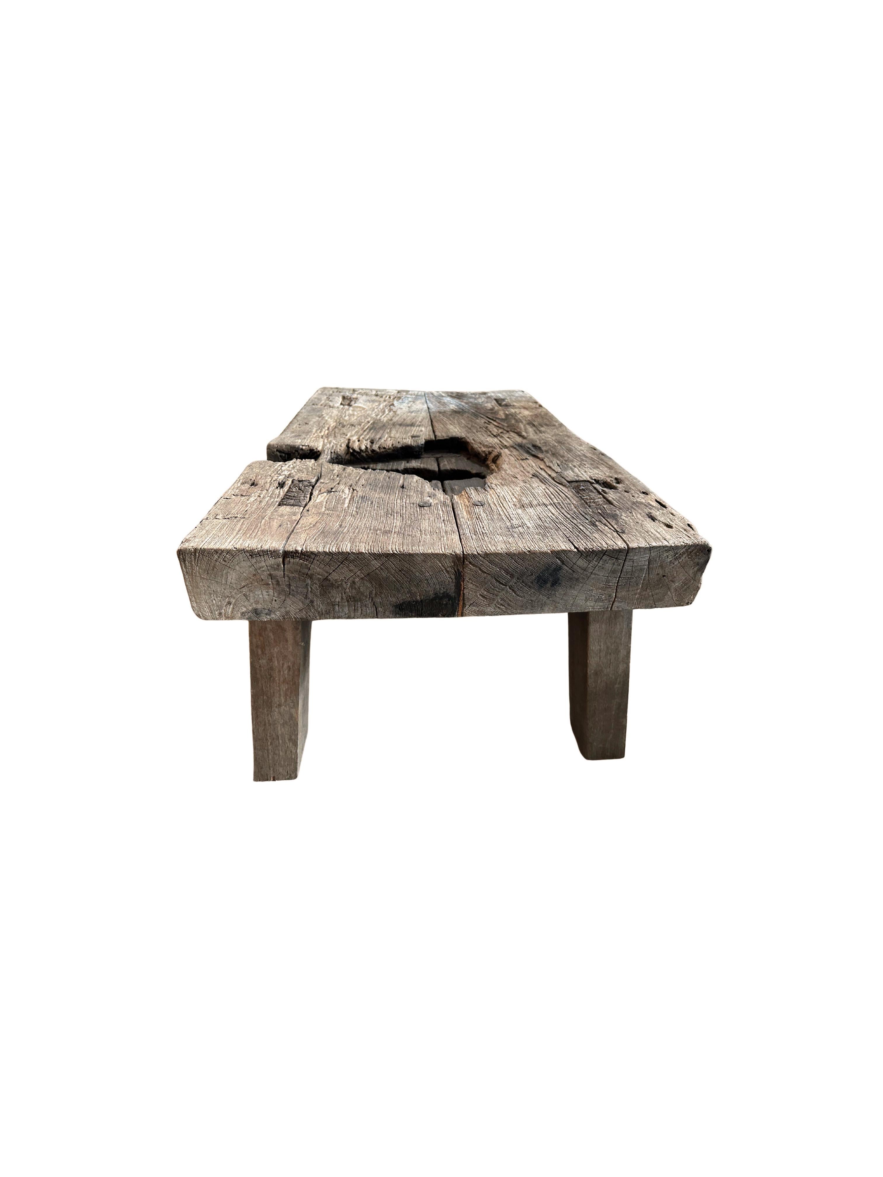 This solid teak coffee table was crafted on the island of Madura off the Northeastern coast of Java, Indonesia. It features angular legs that follow the curvature of each corner. This bench has a charred section on the table top which adds to its