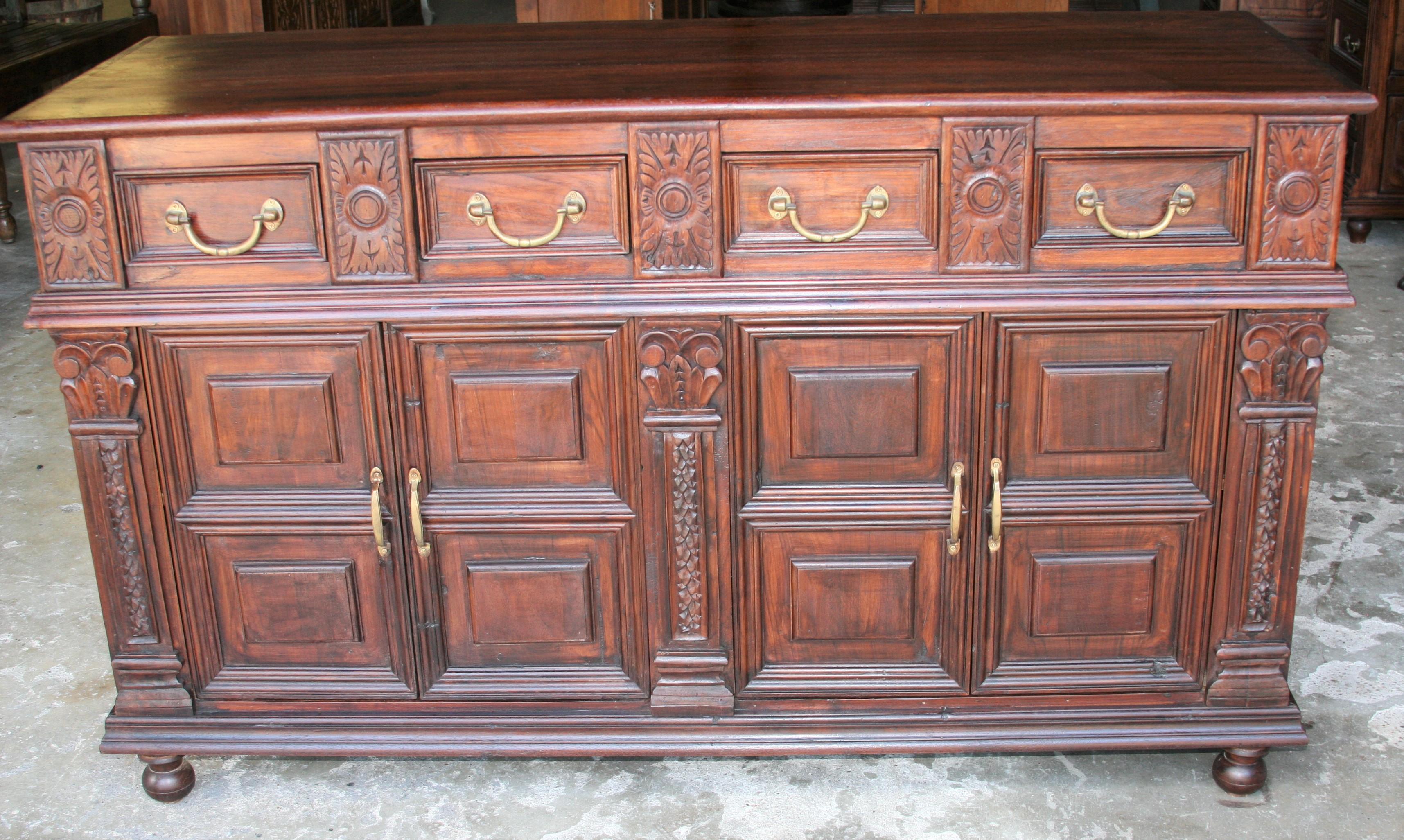 An unique custom made solid teak wood credenza from a French Colonial home in Asia. It has four upper drawers and two large bottom shelves. It is mounted on ball feet. It retains original hand cast brass hardware. It comes from a town Pondicherry in