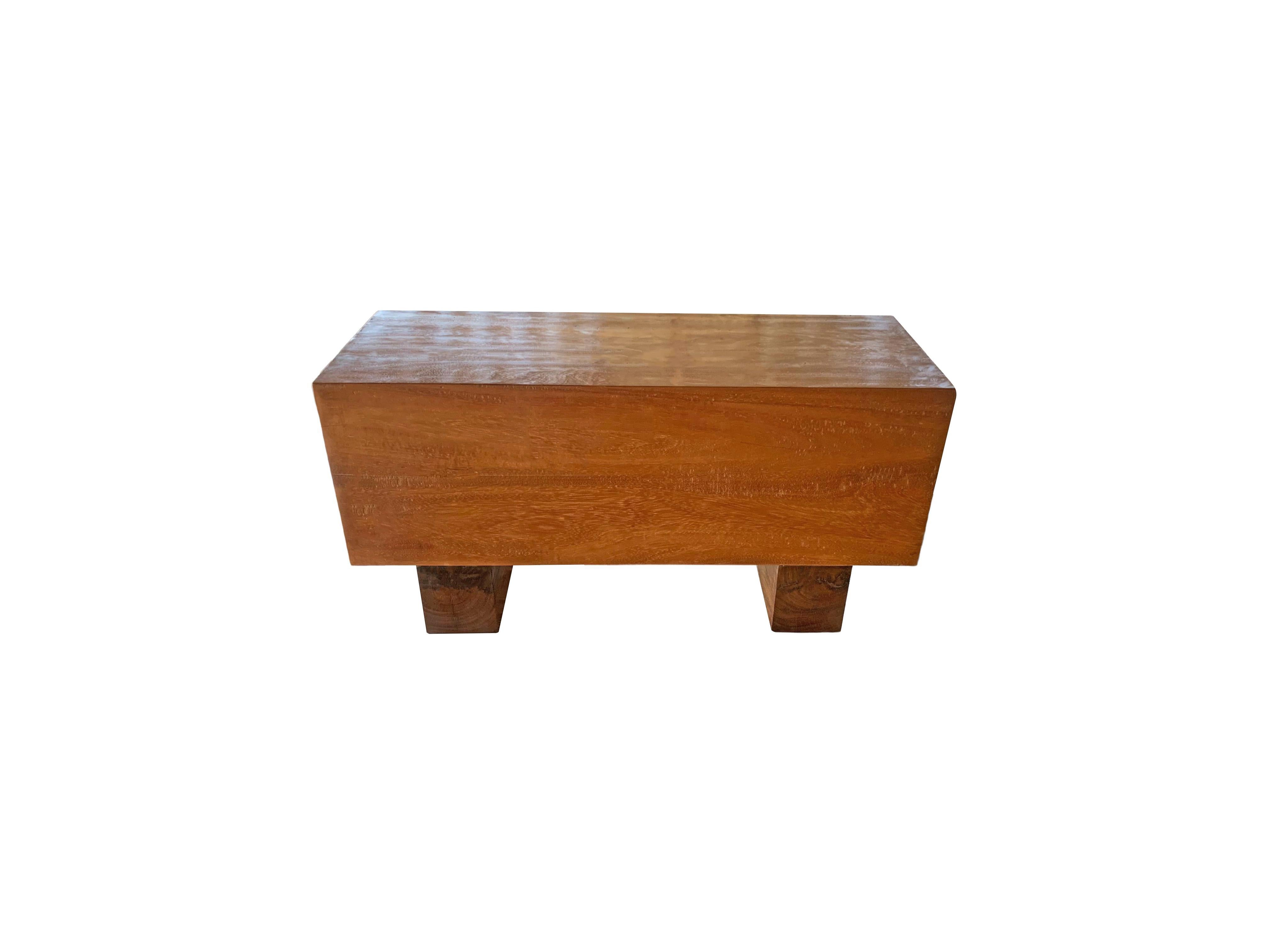 This solid teak wood bench features a wonderful organic form with a mix of wood textures and shades. Elevated by two solid teak wood legs, the seat and legs were carved from single blocks of wood. A wonderful addition to bring warmth to any space.