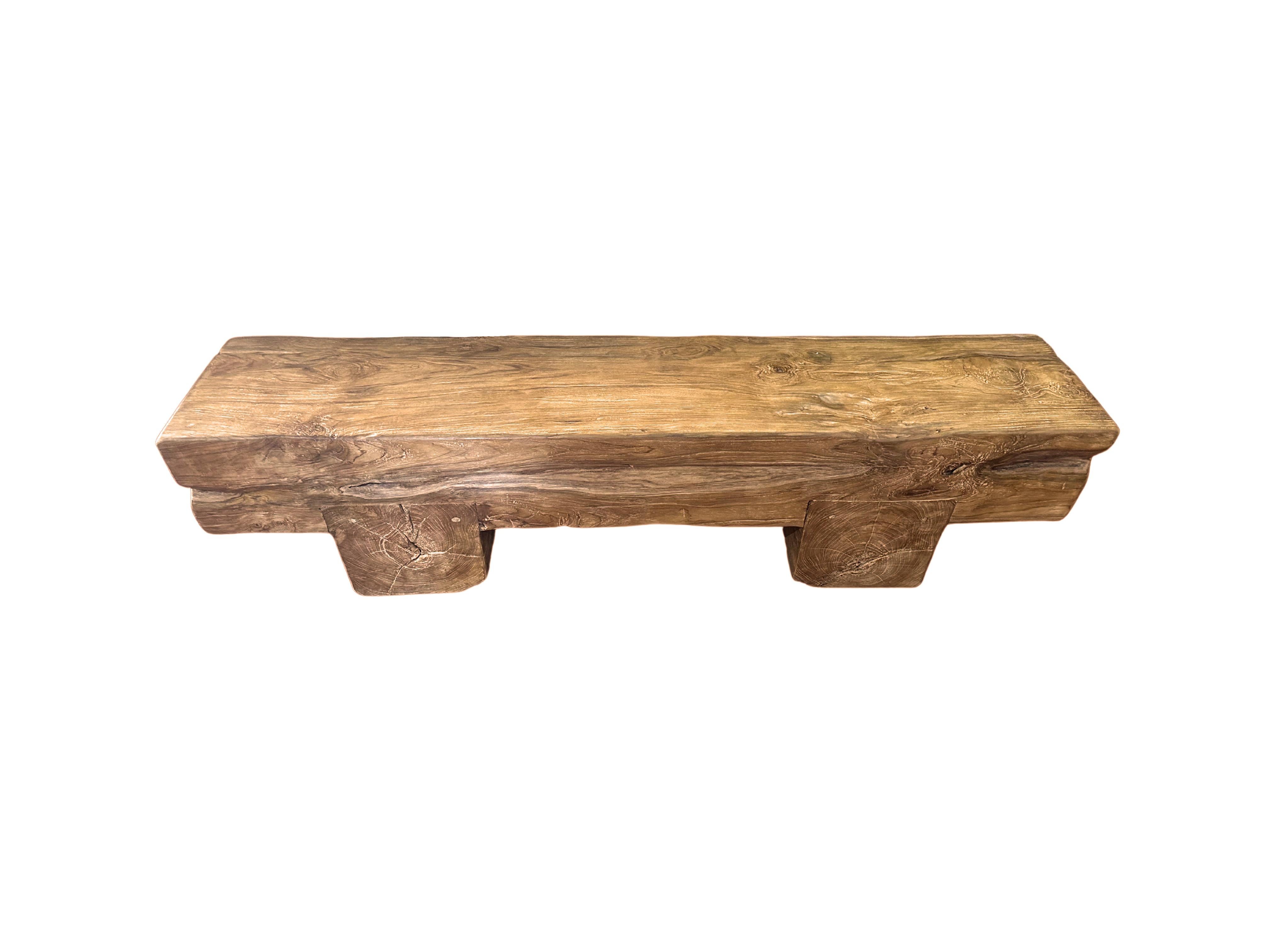 This solid teak wood bench features a wonderful organic form with a mix of wood textures and shades. Elevated by two solid teak wood legs, the seat and legs were carved from single blocks of wood. A wonderful addition to bring warmth to any