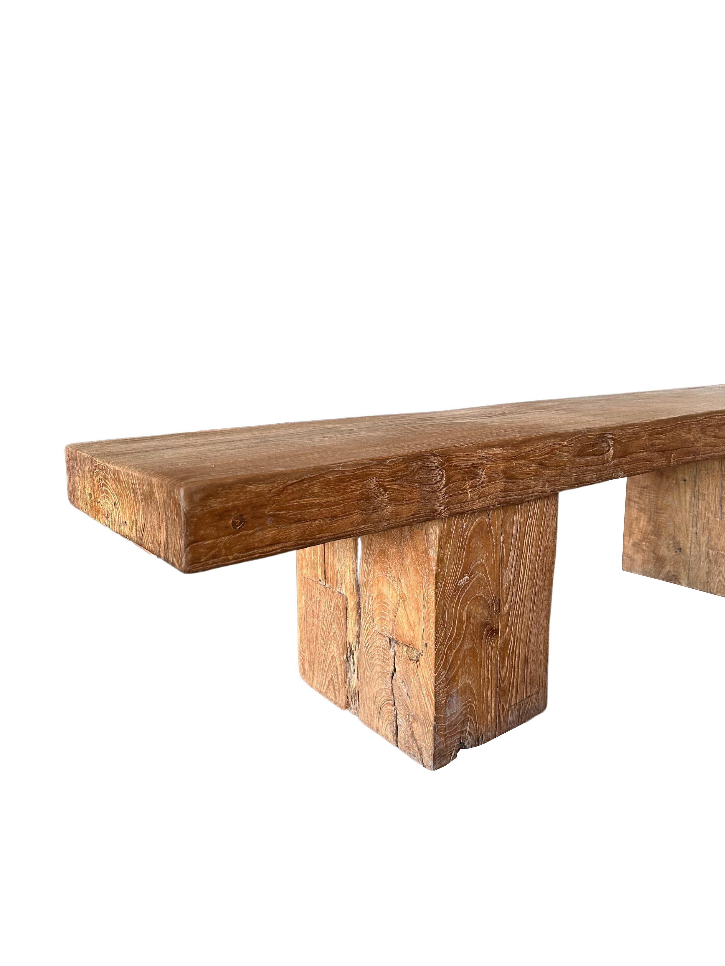 This solid teak wood bench features a wonderful organic form with a mix of wood textures and shades. Elevated by two solid teak wood legs, the seat and legs were carved from single blocks of wood. A wonderful addition to bring warmth to any space.