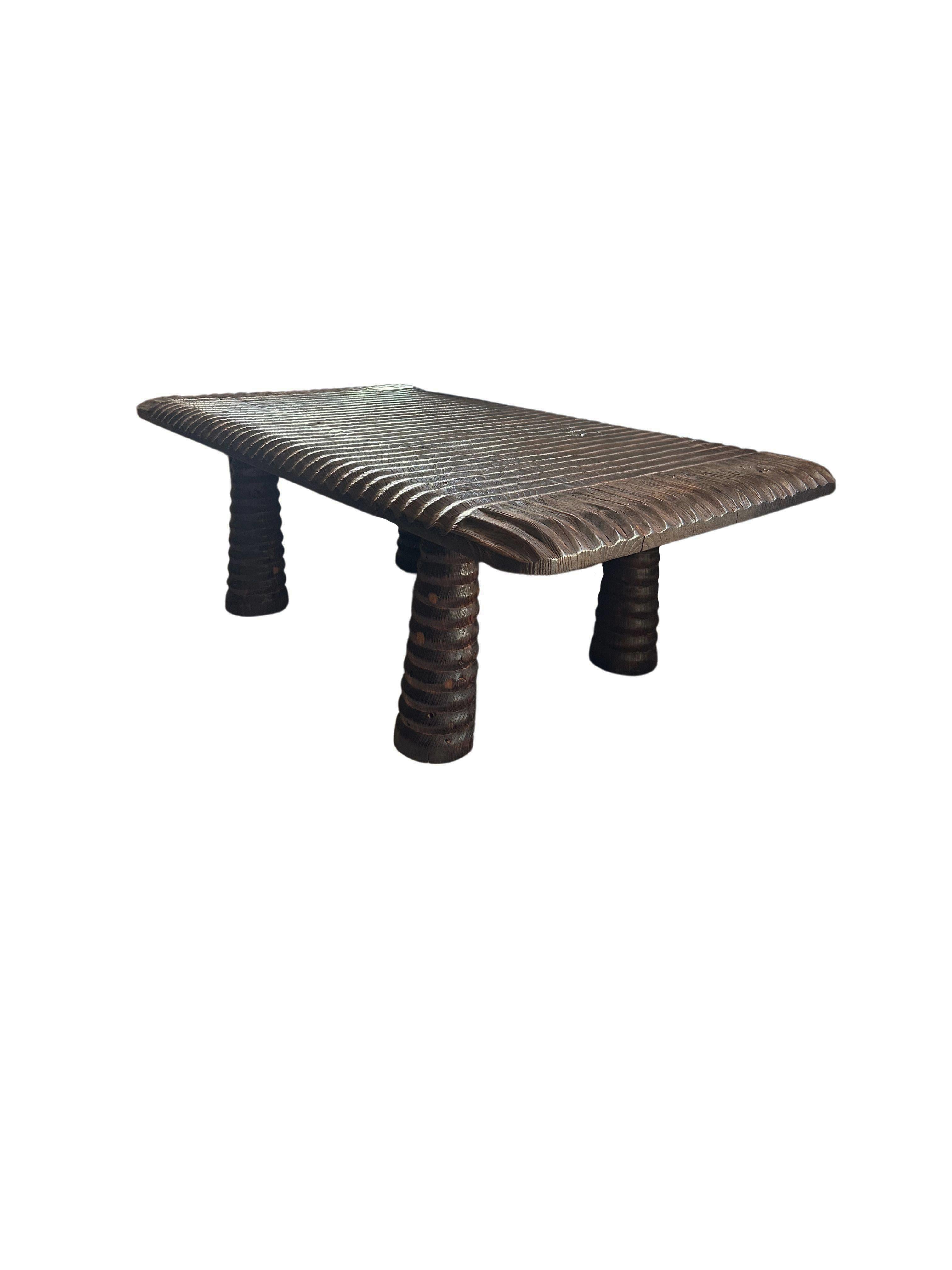 Esta llamativa mesa de centro está fabricada en madera de teca, mostrando la belleza natural de las vetas de la madera al tiempo que presenta un exclusivo acabado quemado que añade un aire de sofisticación y encanto rústico. Un elemento de diseño