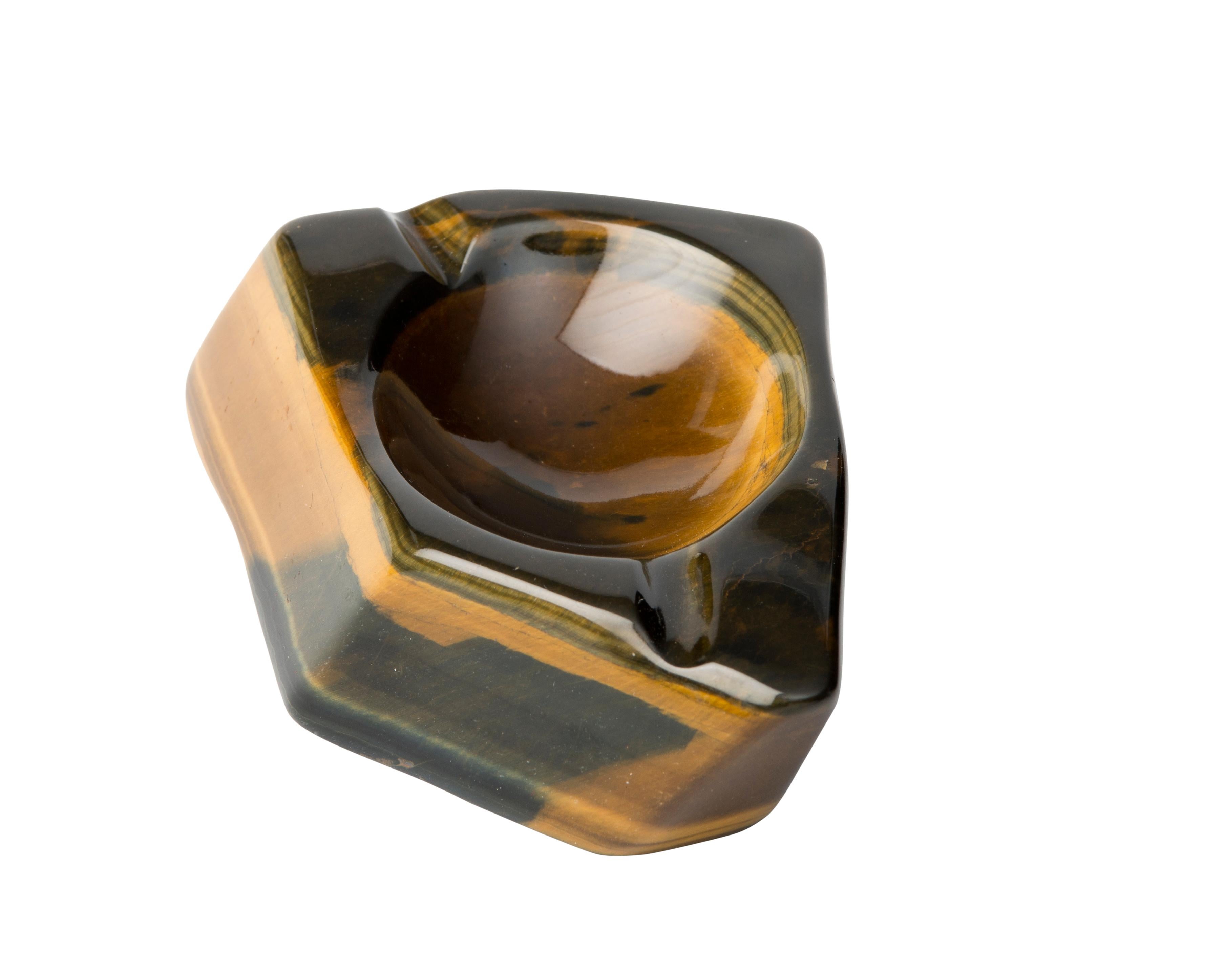 Solid tiger eye stone ashtray, polished, from South Africa. 
Tiger's eye is a mineral with a silky lustre and distinctive red-brown golden coloring. In the 16th century it was more precious than gold, often used as eyes in deity statues, also worn