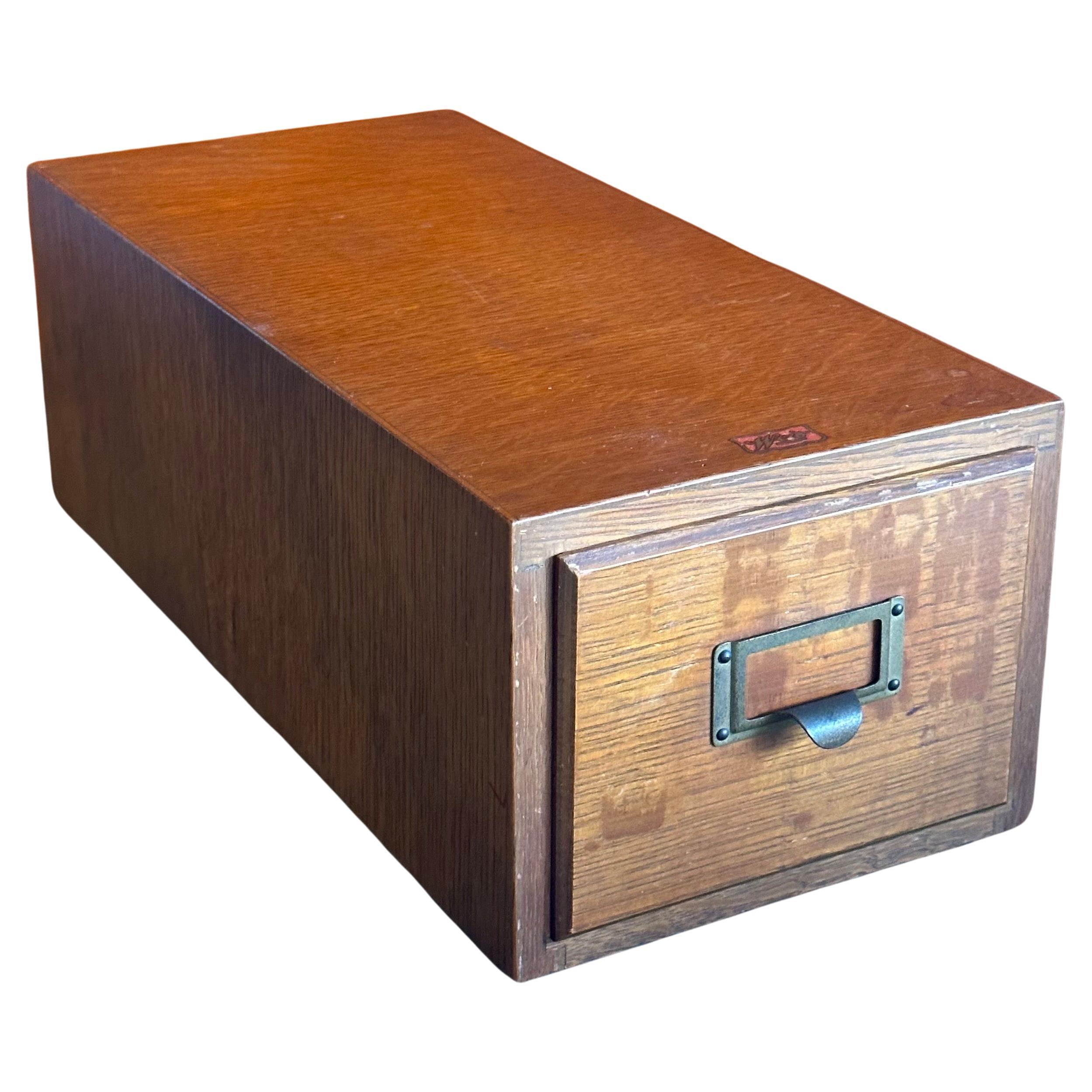 A solid tiger oak single card catalog box with brass handle by Weis, circa 1940s This solid oak cabinet is constructed with gorgeous dovetail joints, a finished backside and a solid brass handle.  The piece is in very good vintage condition and