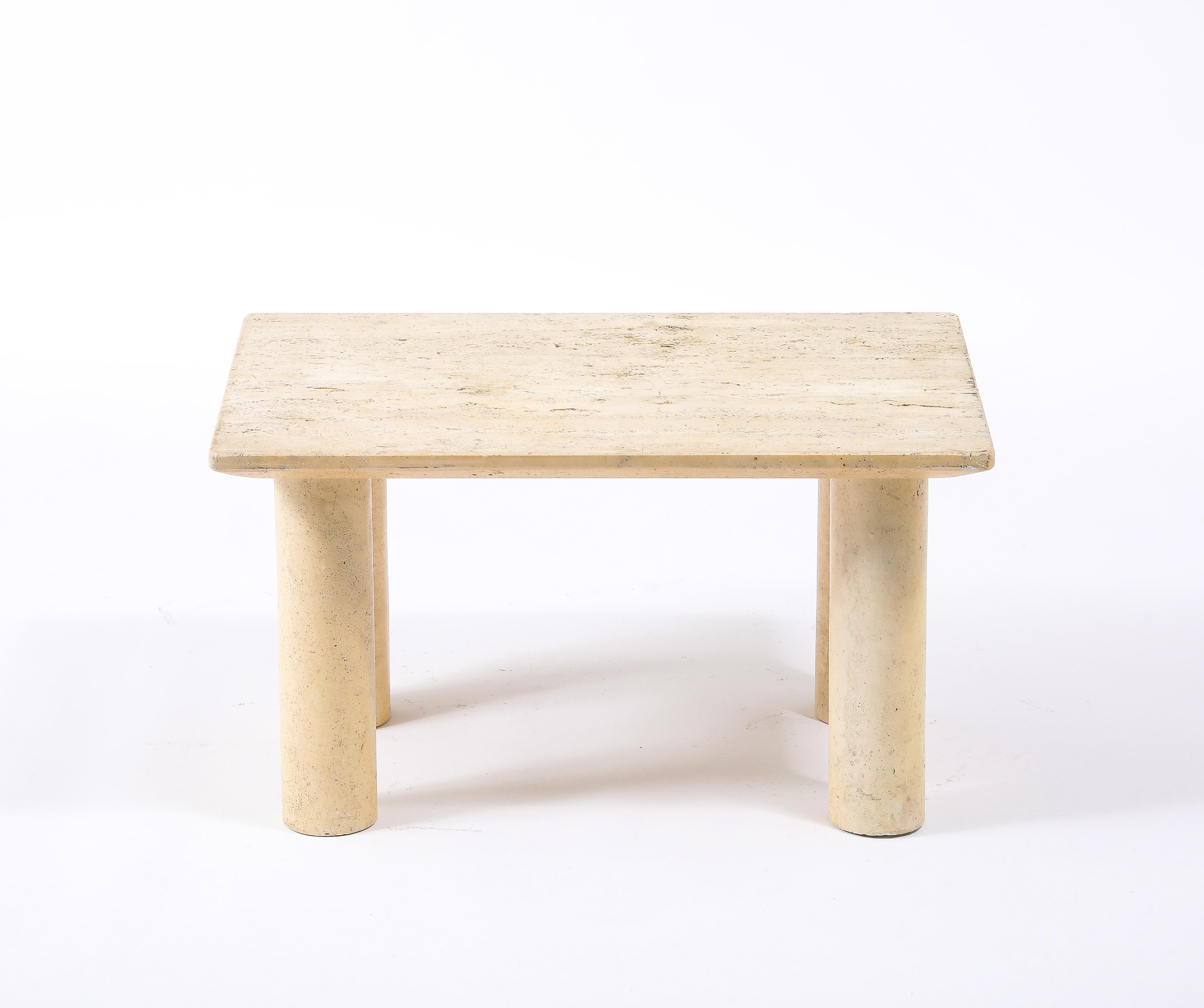 Solid Travertine table, a rectangular top with a chamfered lower edge supported by large round travertine legs.
