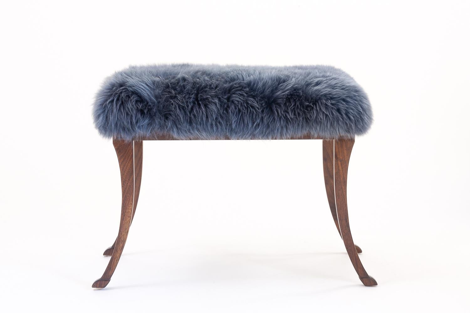 Reminiscent of the classical Greek period, the Eros bench features typical piano bench dimensions. It is crafted in solid walnut with traditional joinery, hand carved feet and escutcheons and upholstered in black, white or gray Mongolian fur. Each