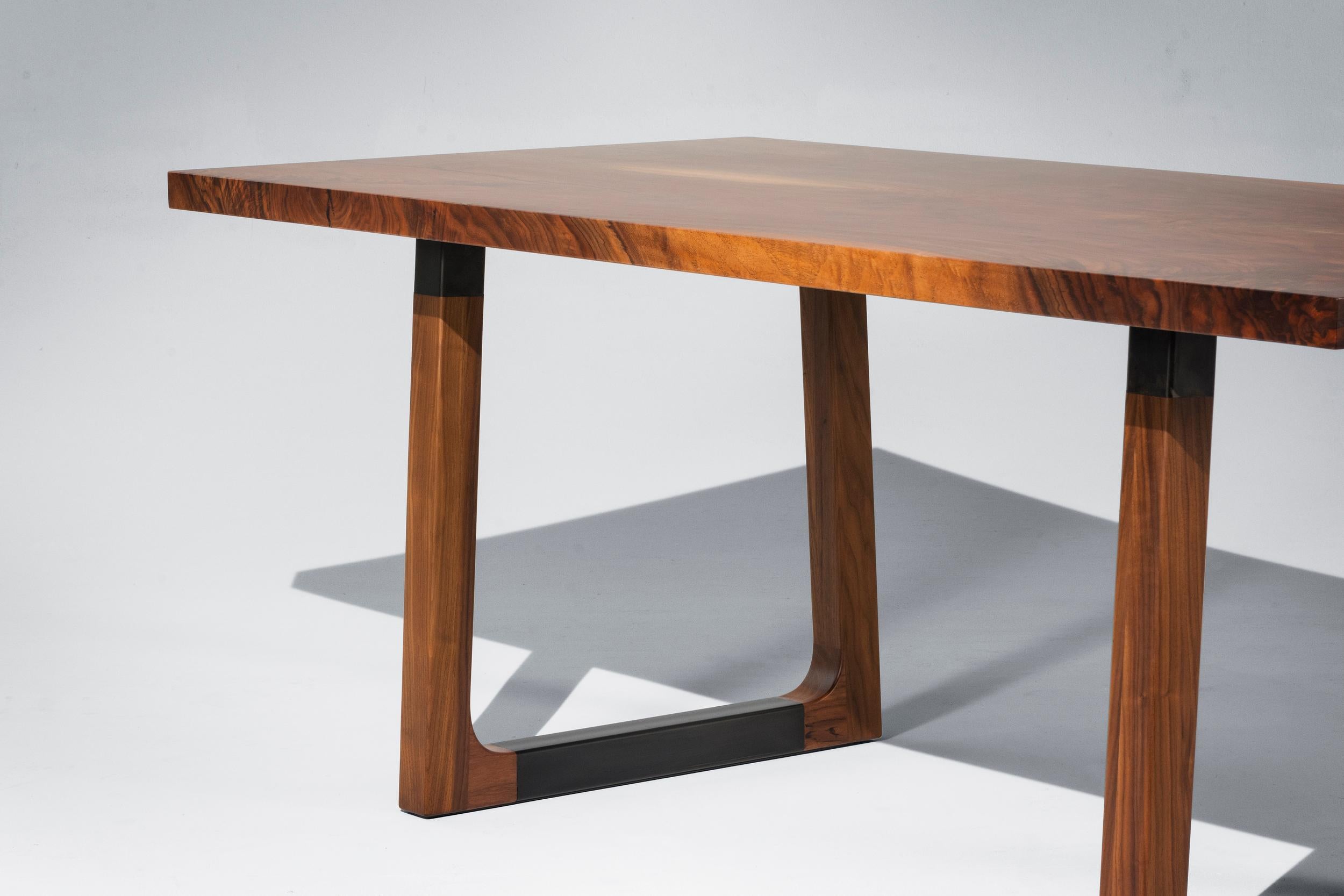 The Campau dining table is made of a bookmatched solid walnut top and solid walnut bases with blackened steel inserts. This simple and modern table emphasizes the high-quality materials and craftsmanship that went into producing this piece. 

This