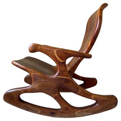 Vieille chaise à bascule moderniste sculptée en noyer massif