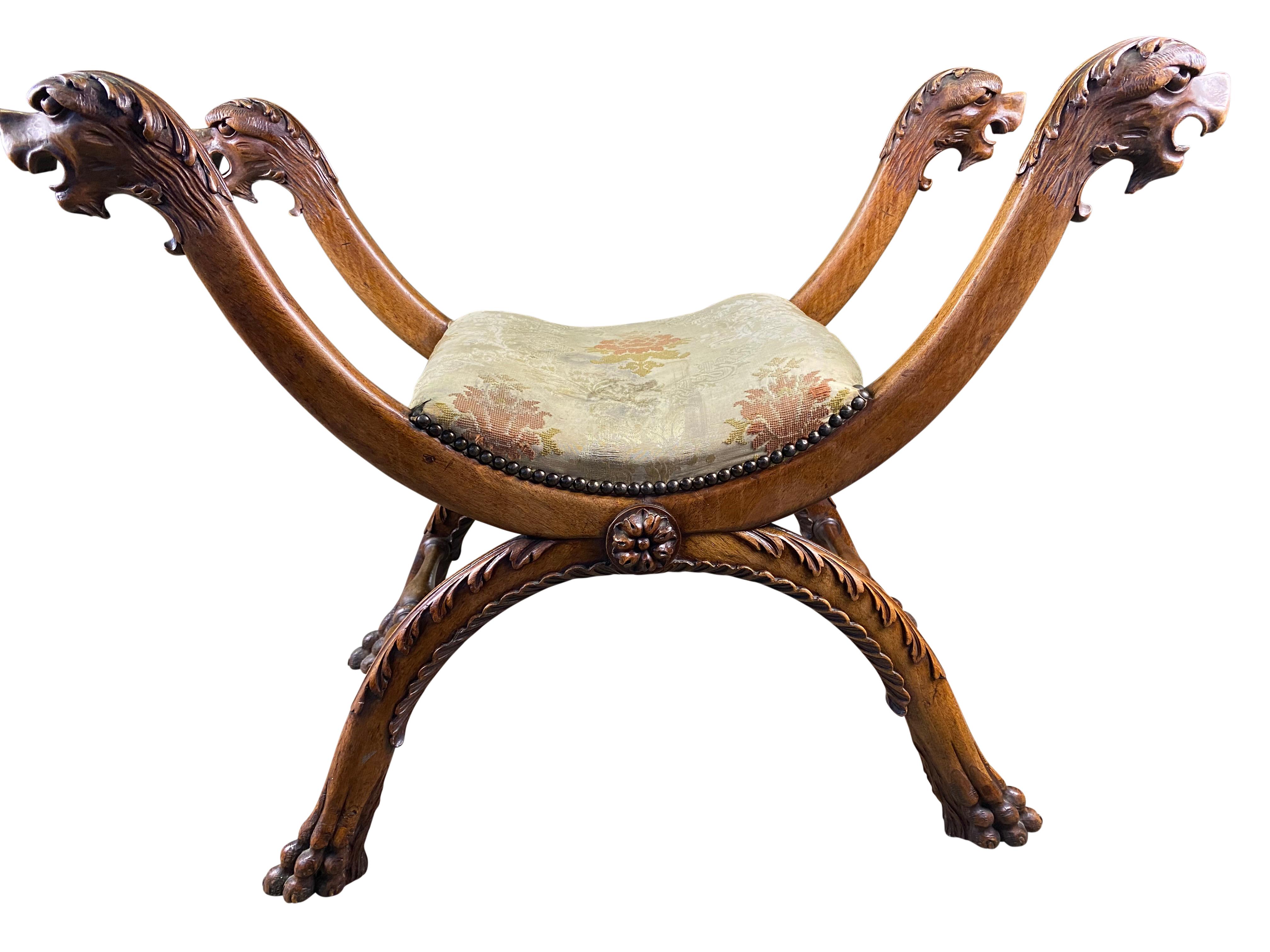 An interestingly themed 18th century walnut stool with two arched beams above the stretchers, each with two creature heads attached at the end. Each beam is uniquely carved and the stool includes its original cushioning, with beautifully carved paws