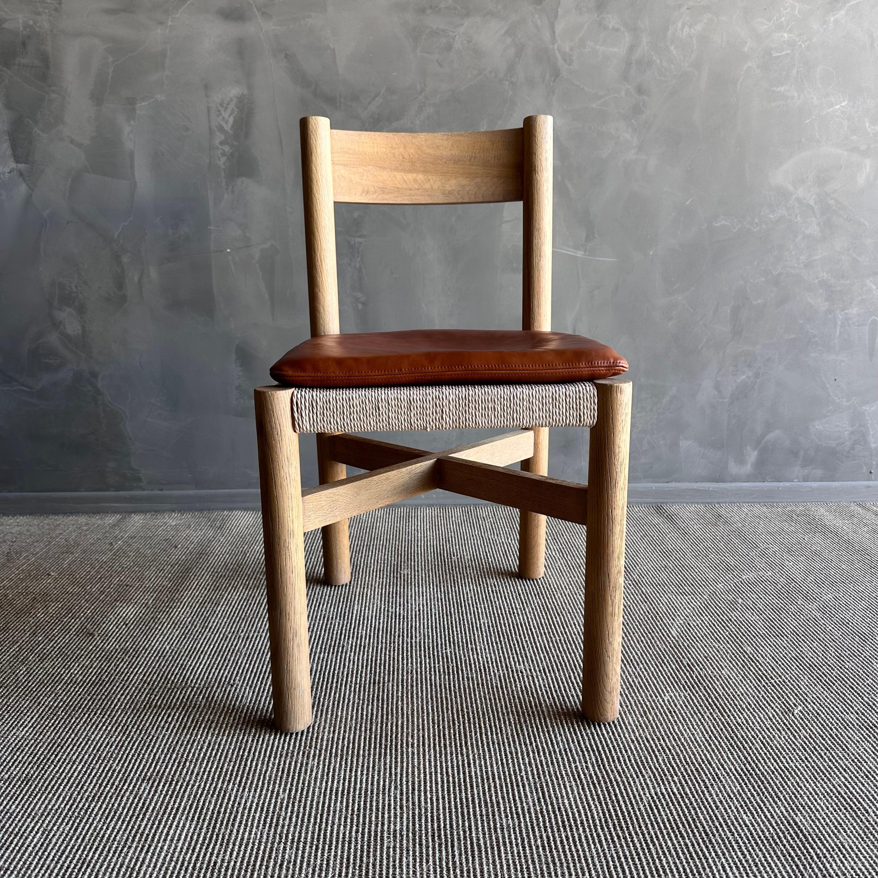 Introducing the Ellie White Oak Dining Chair, crafted from solid white oak with a natural finish that showcases its beautiful grain texture. This elegant chair features a woven seat for a touch of vintage charm and comes with a comfortable removable