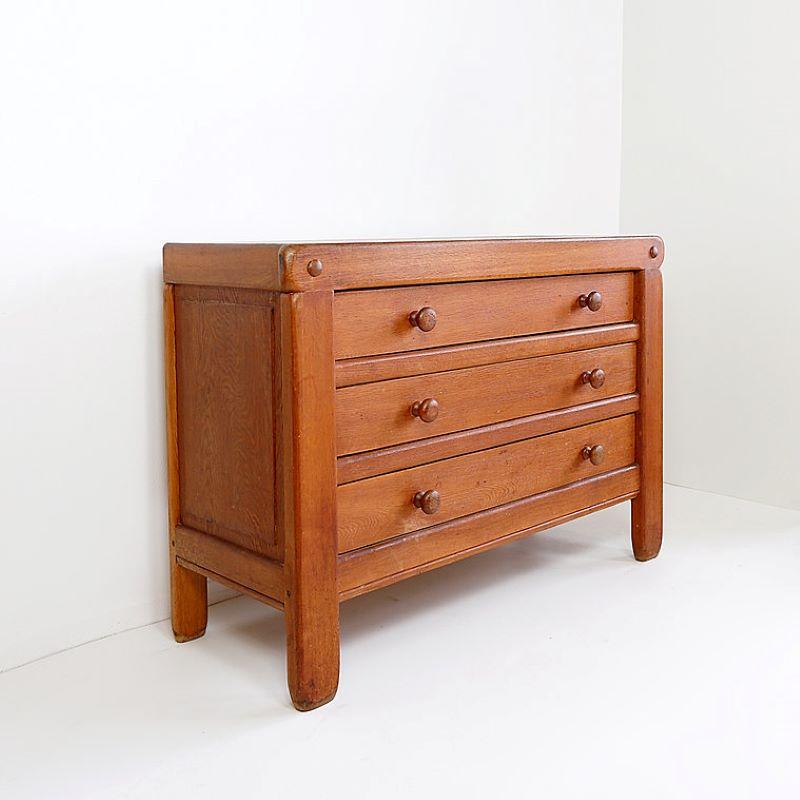 Chest of three drawers in a solid redish wood in the style of parisian designer Pierre Chapo